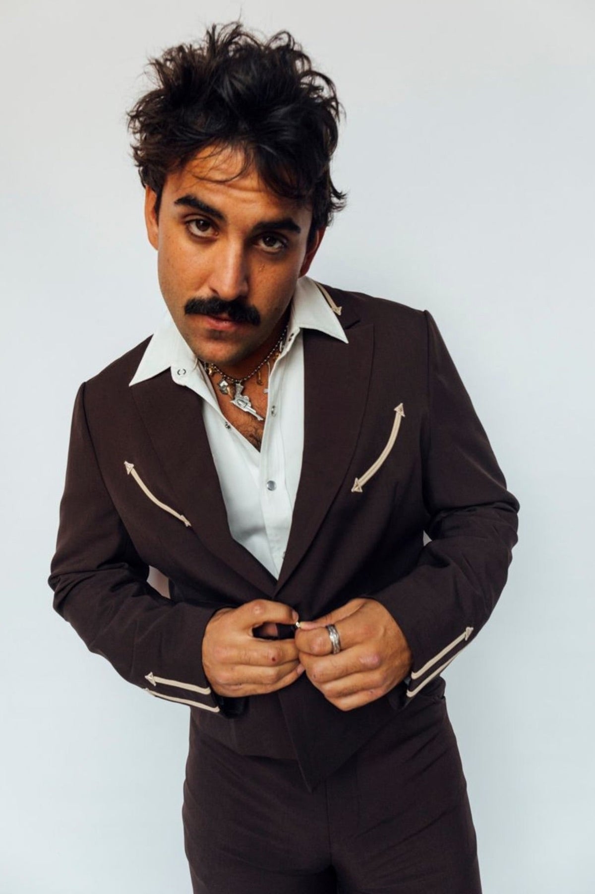 Man wearing the H Bar C Calamity jacket in chocolate brown with cream arrow details, inspired by a 1970s H Bar C jacket.