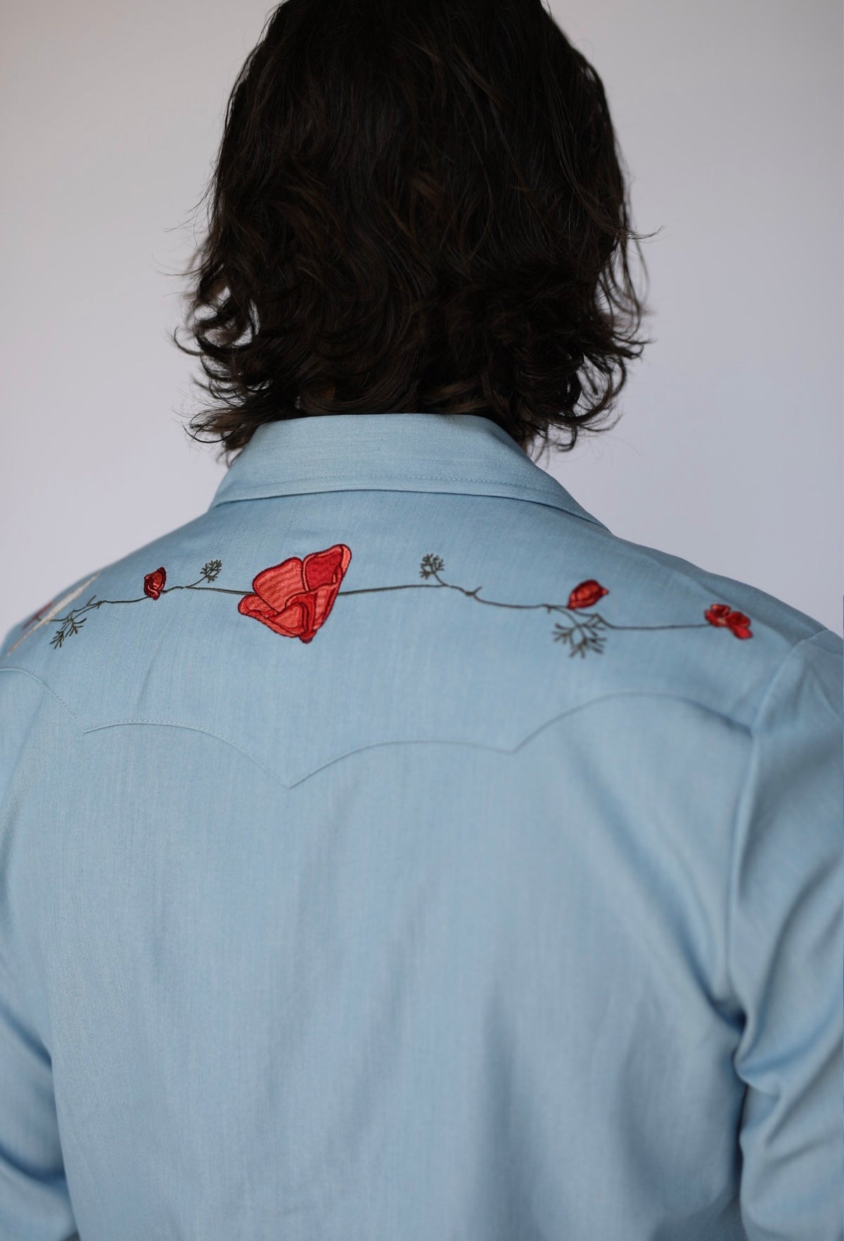 Back yoke of the HBarC x Gibson Dove light blue chambray shirt with embroidered red poppies on a vine.