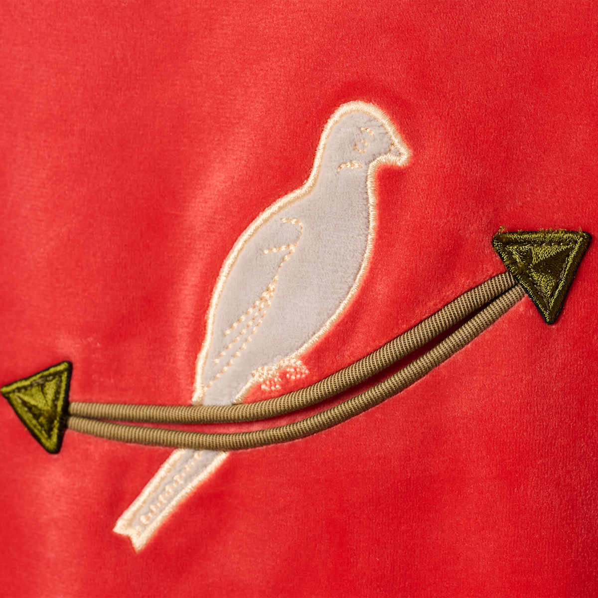 Close-up of the white dove perched on an arrow embroidered on the HBarC x Gibson Dove red velour jacket.