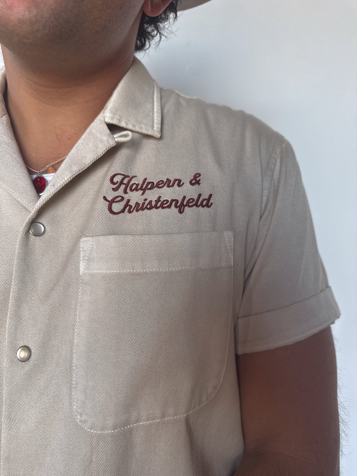 Chest logo detail of the H Bar C Halpern & Christenfeld bowling shirt with red script embroidery.