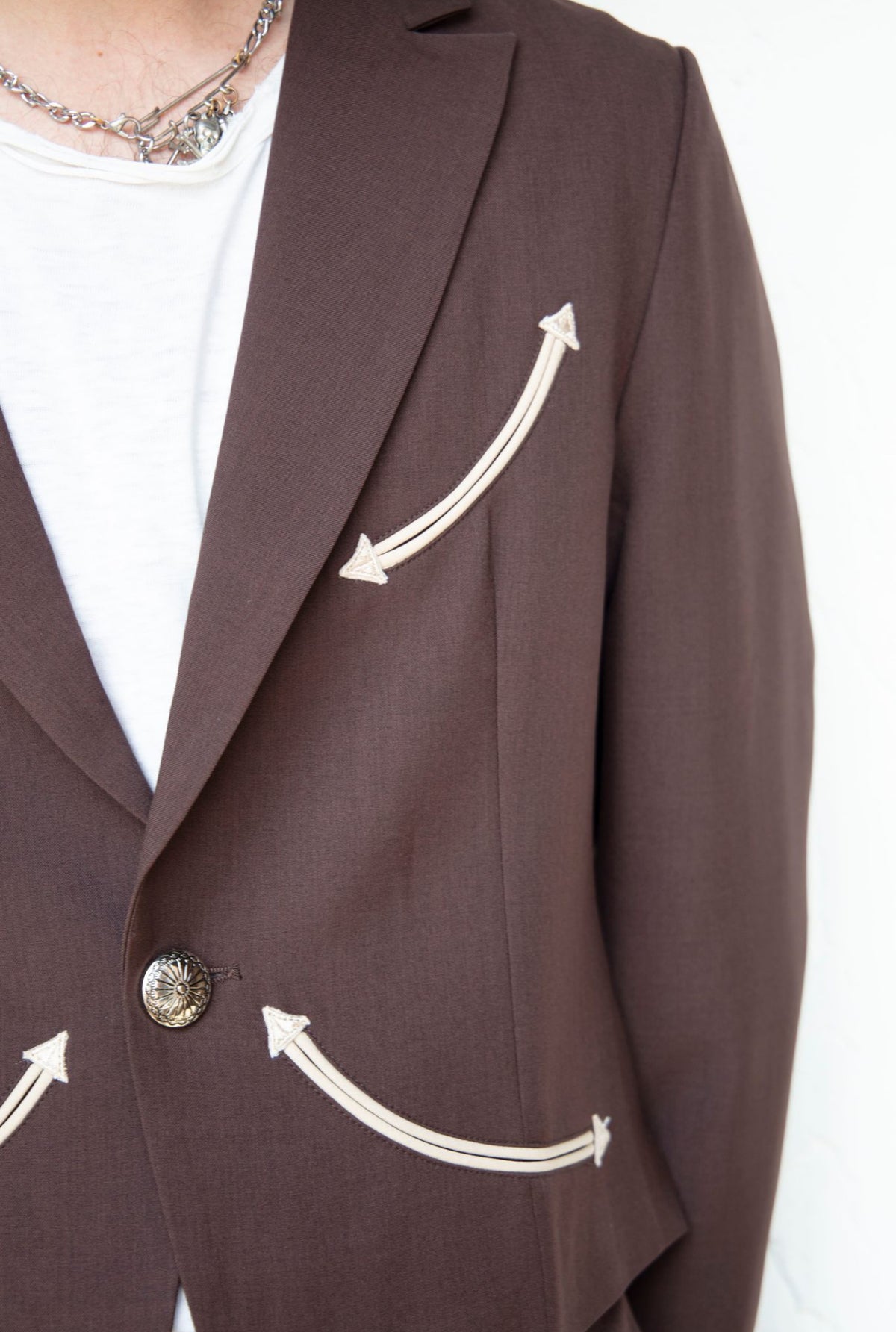 Detail of the cream piped arrow smile pocket on the H Bar C Calamity chocolate jacket.