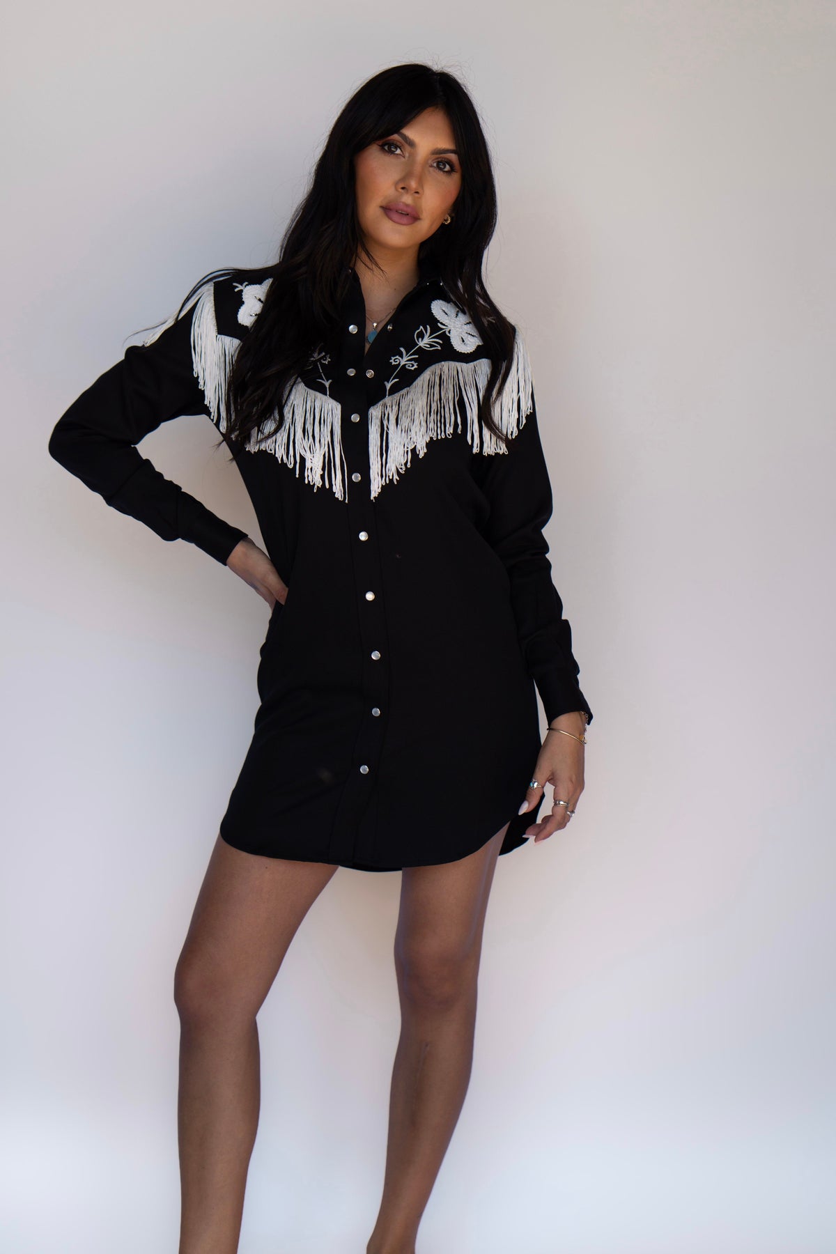 Woman wearing the H Bar C Roswell women's dress in black with white fringe and embroidery, a shirt dress version of the Taos.