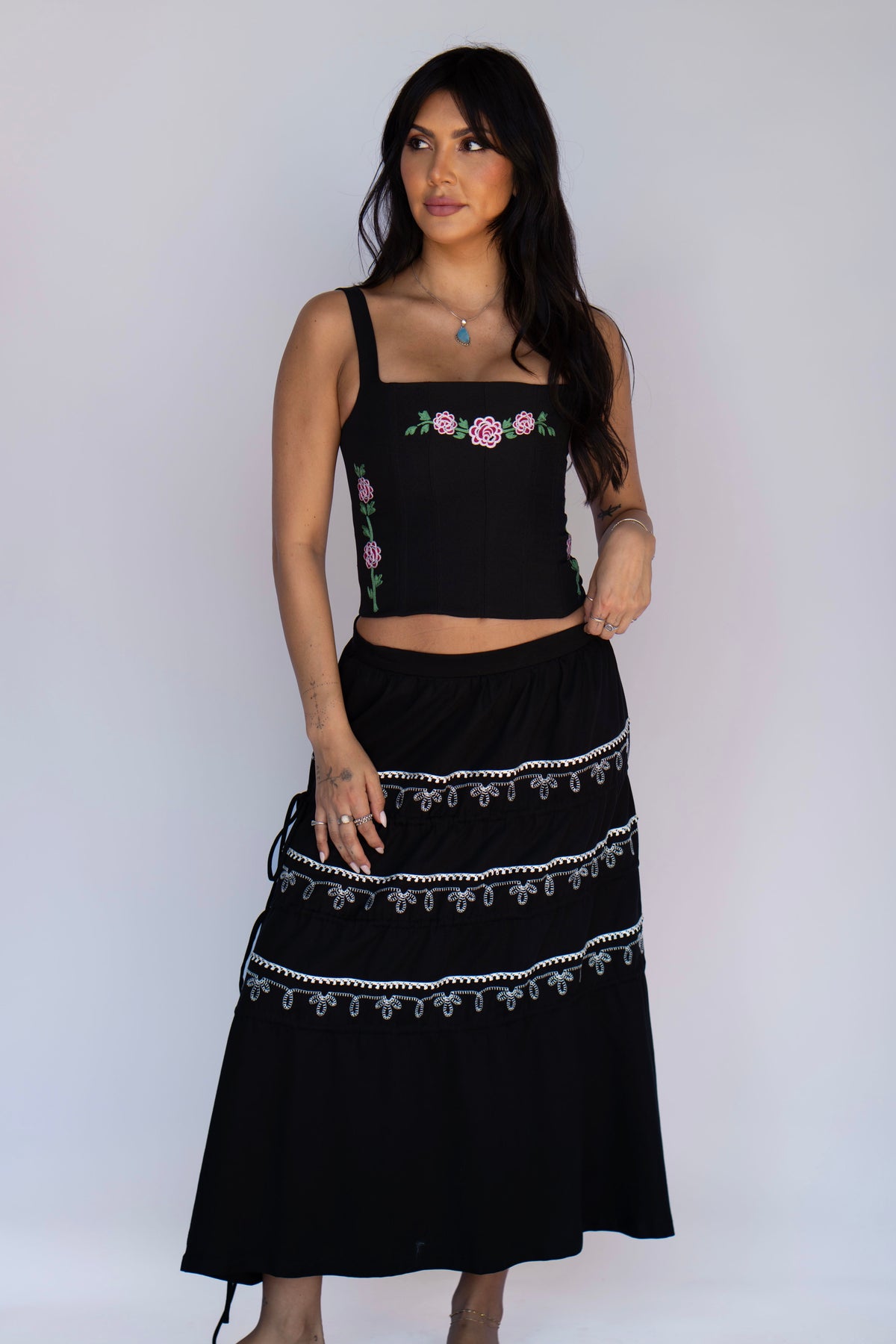 Woman wearing the H Bar C Coachella skirt in black with white Bolero-inspired embroidery and three adjustable tiers, with the Canterbury corset.