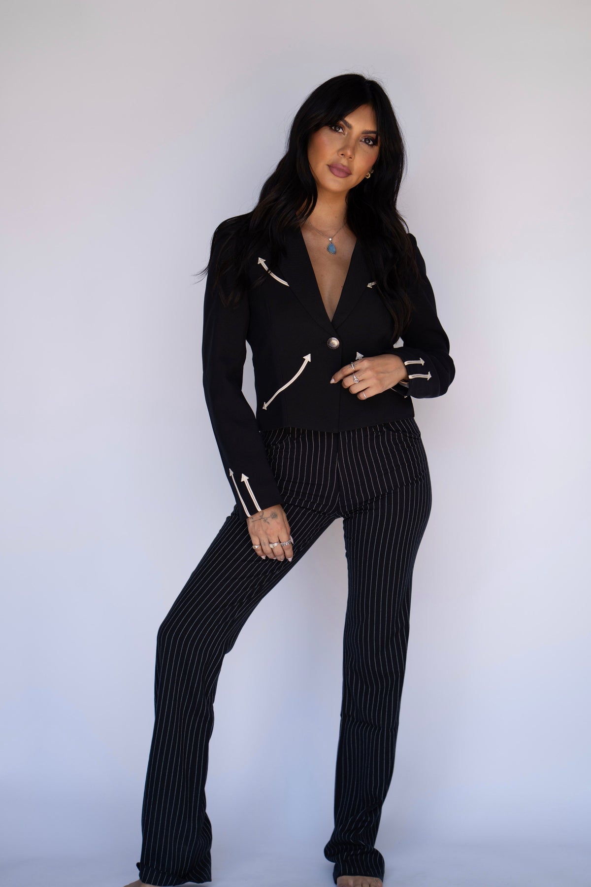 Woman posing in the H Bar C Calamity women's black western blazer with pinstripe trousers.