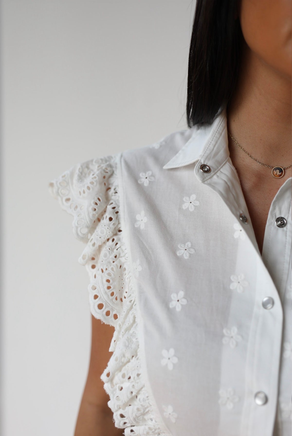 Close-up of the eyelet lace flutter sleeve and snap front on The Lexington H Bar C white top.