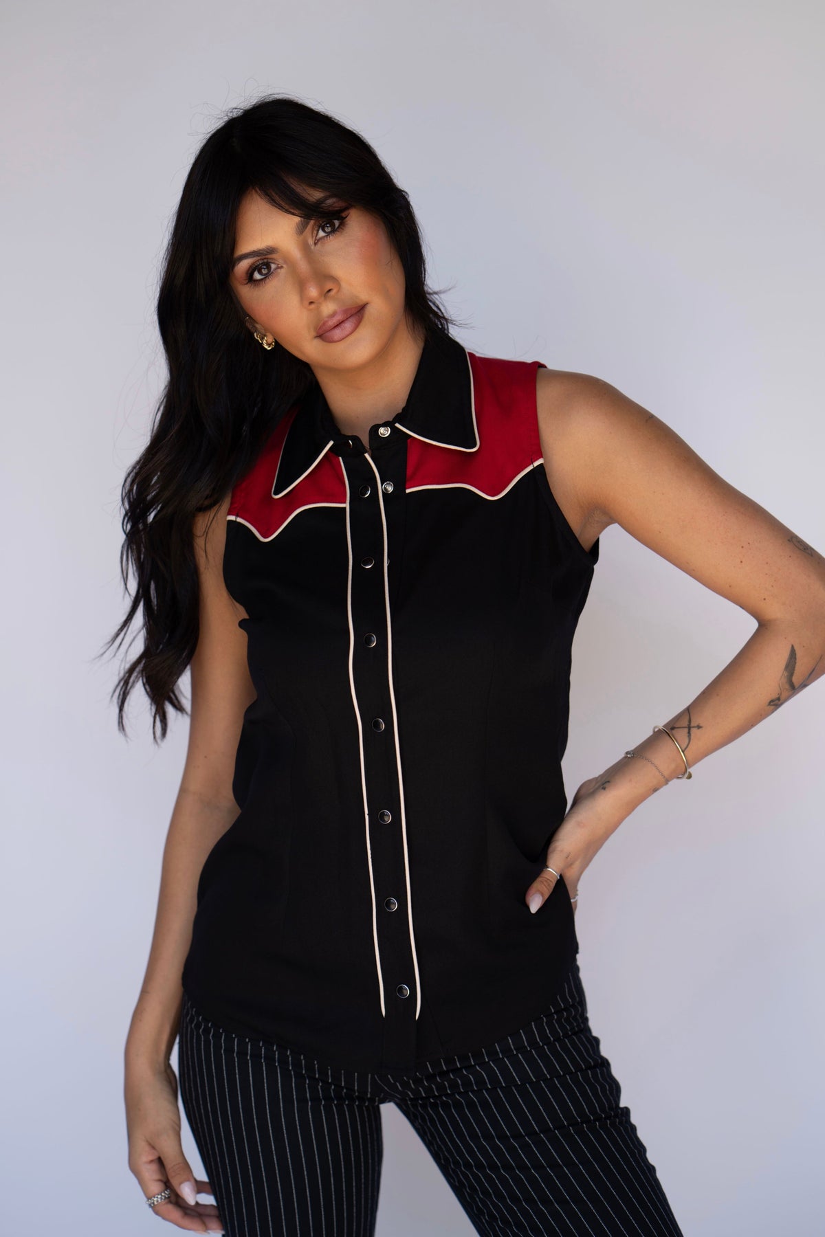 Woman wearing the H Bar C Atlanta women's sleeveless shirt in black with a red yoke and cream piping, with pinstripe pants.