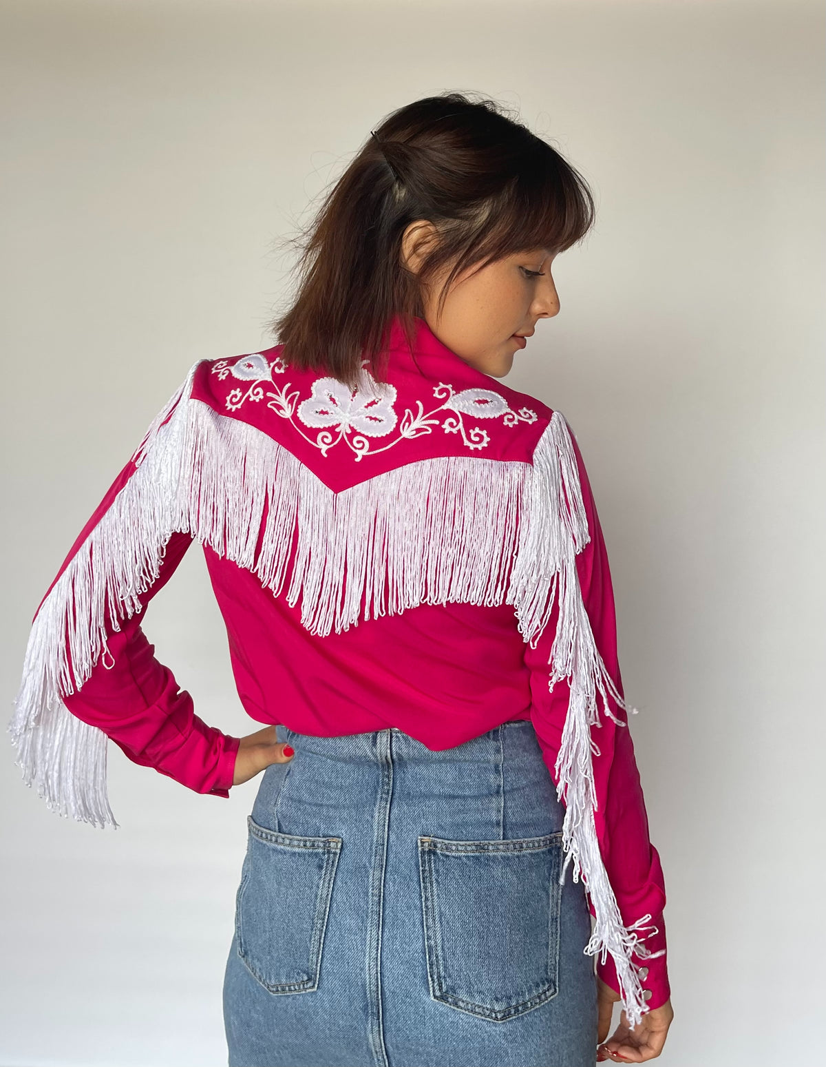 Side view of the H Bar C Taos pink shirt showing white fringe on the sleeves.