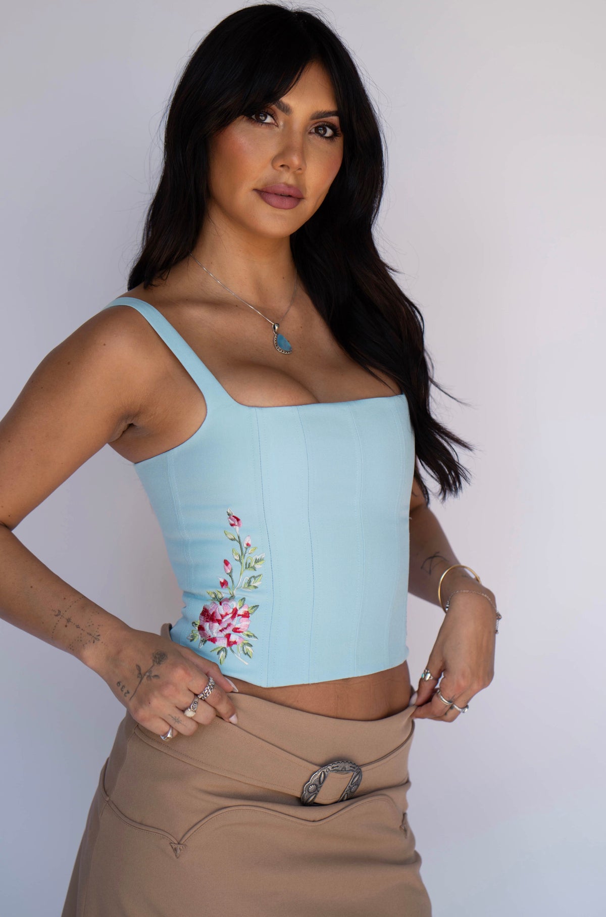 Three-quarter view of the H Bar C Abilene light blue corset with floral embroidery and a tan skirt.