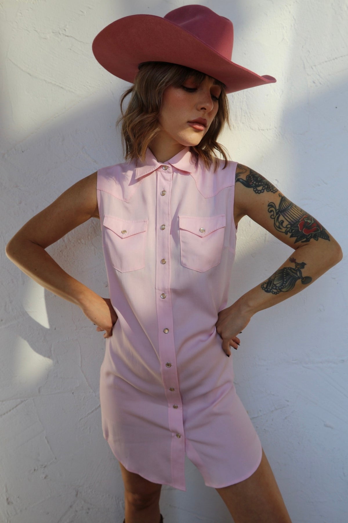 Woman in a red cowboy hat wearing the H Bar C Palm Beach women's dress in pink, a sleeveless western shirt dress.
