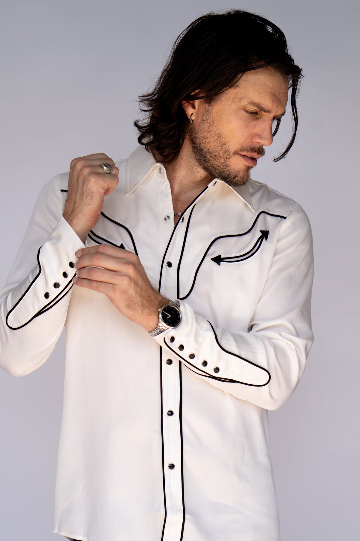 Man fastening the black piped rodeo cuff of the H Bar C San Fernando white western shirt.