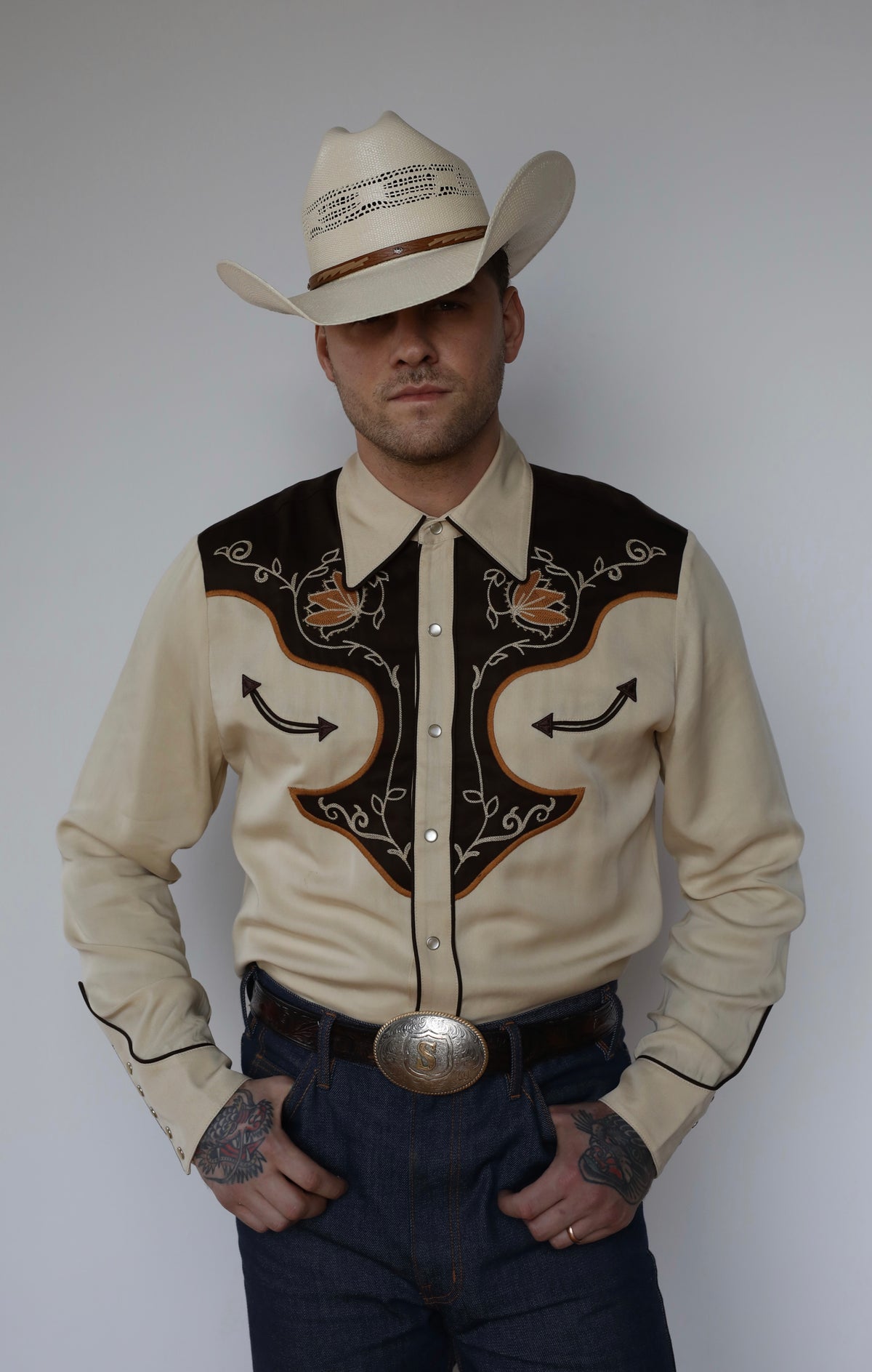 Front view of the H Bar C Santa Barbara cream and brown embroidered western shirt with jeans and buckle.