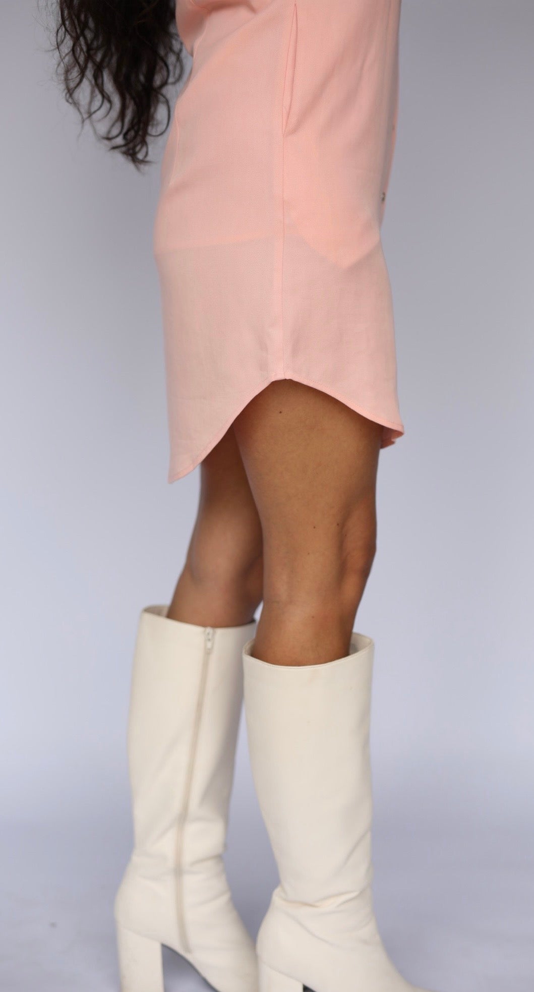 Curved hem of the H Bar C Palm Beach peach dress with white heeled boots.