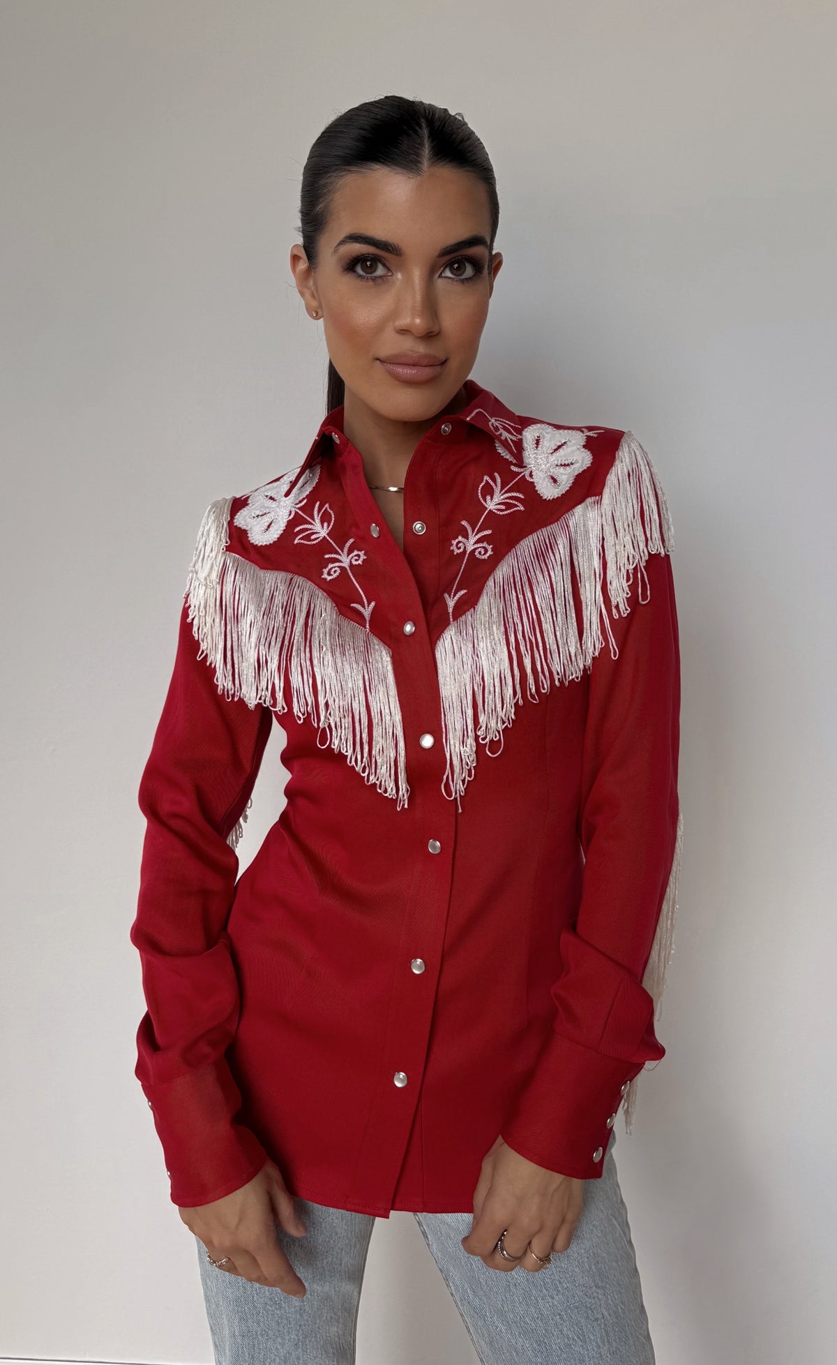 Front view of the H Bar C Taos red fringe western shirt for women with jeans.