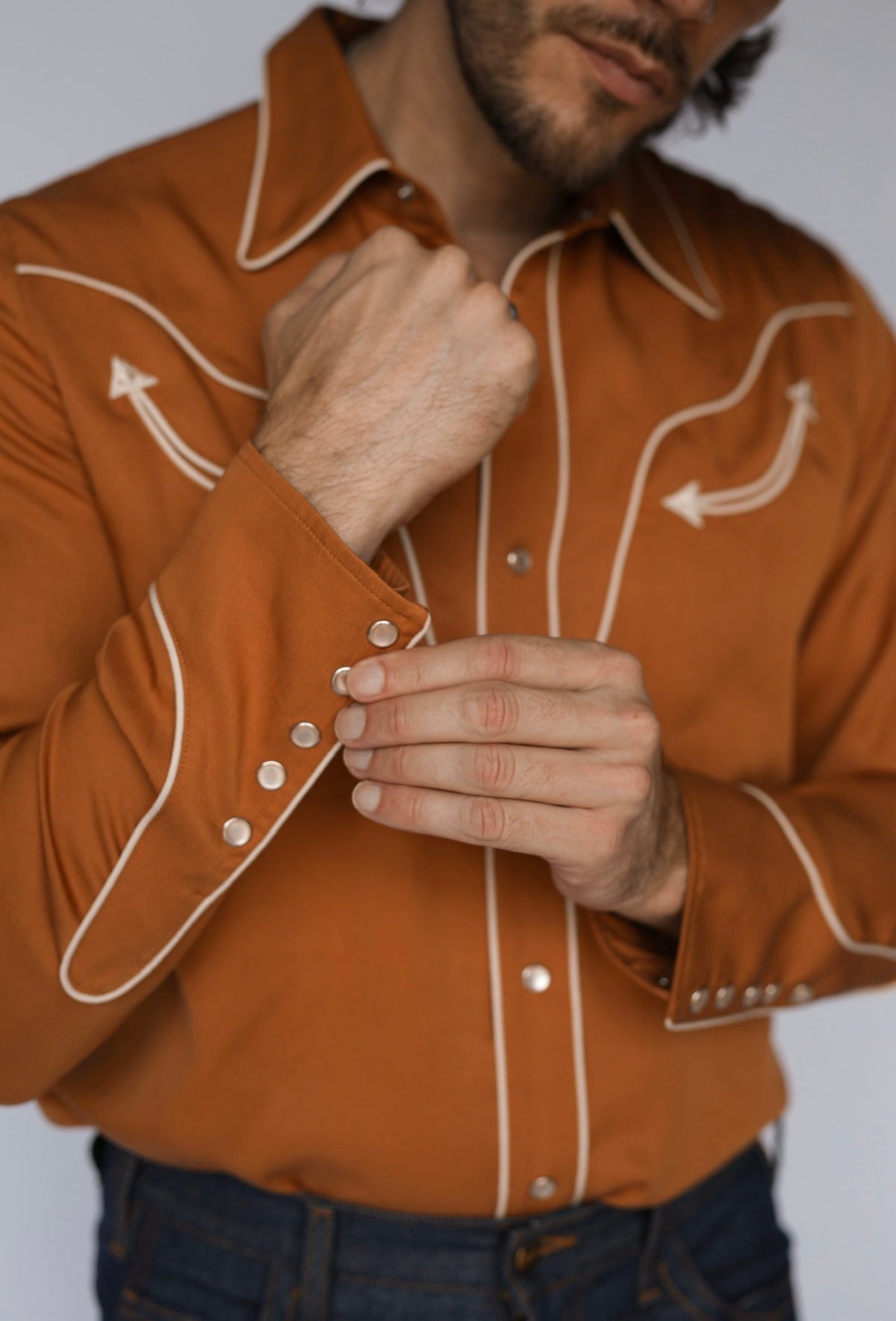 Detail of the pearl snaps and piped arrow yoke on the H Bar C San Fernando men's burnt orange western shirt.