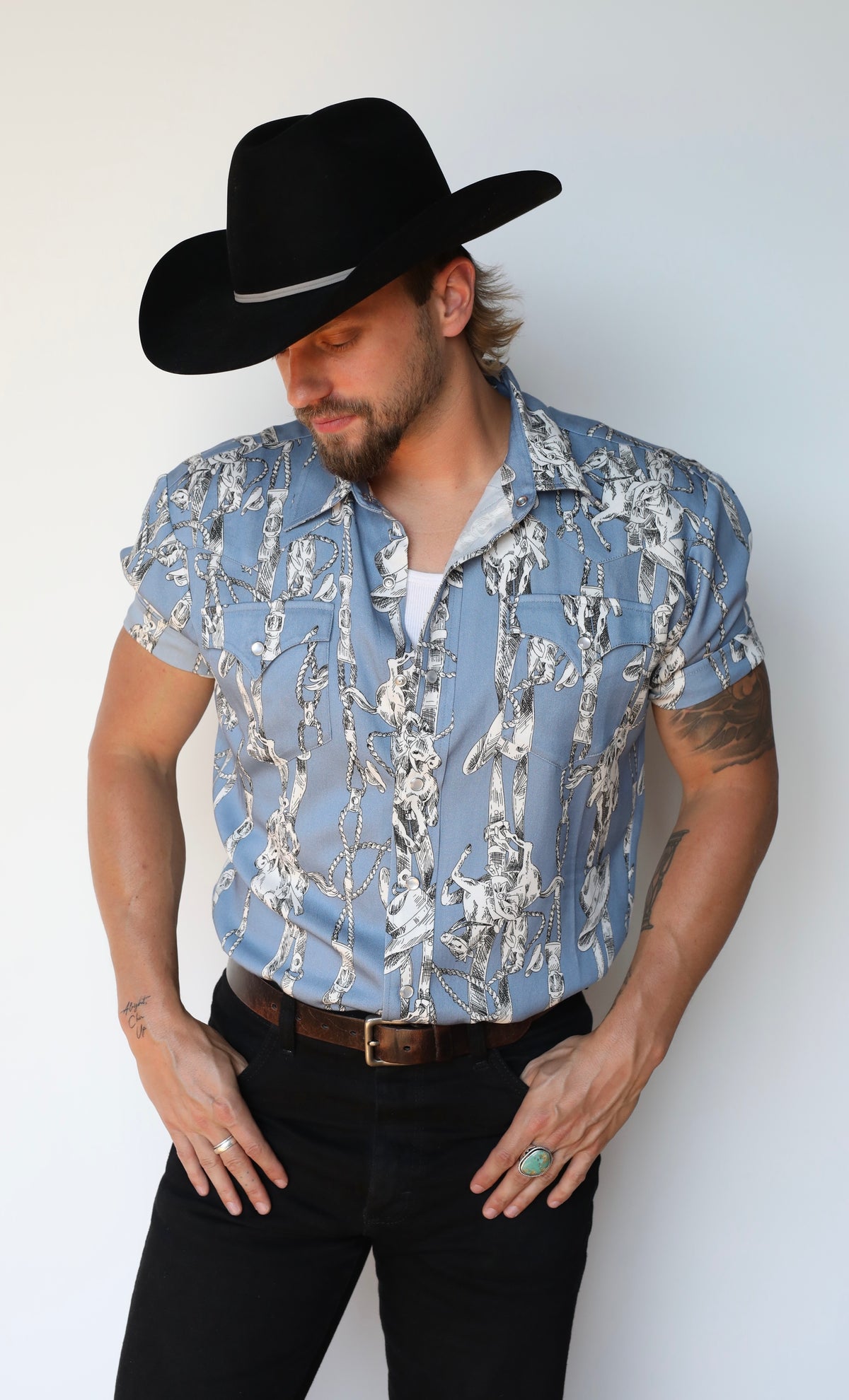 Man wearing the H Bar C Newport Breckenridge printed short sleeve shirt with a black hat and belt.