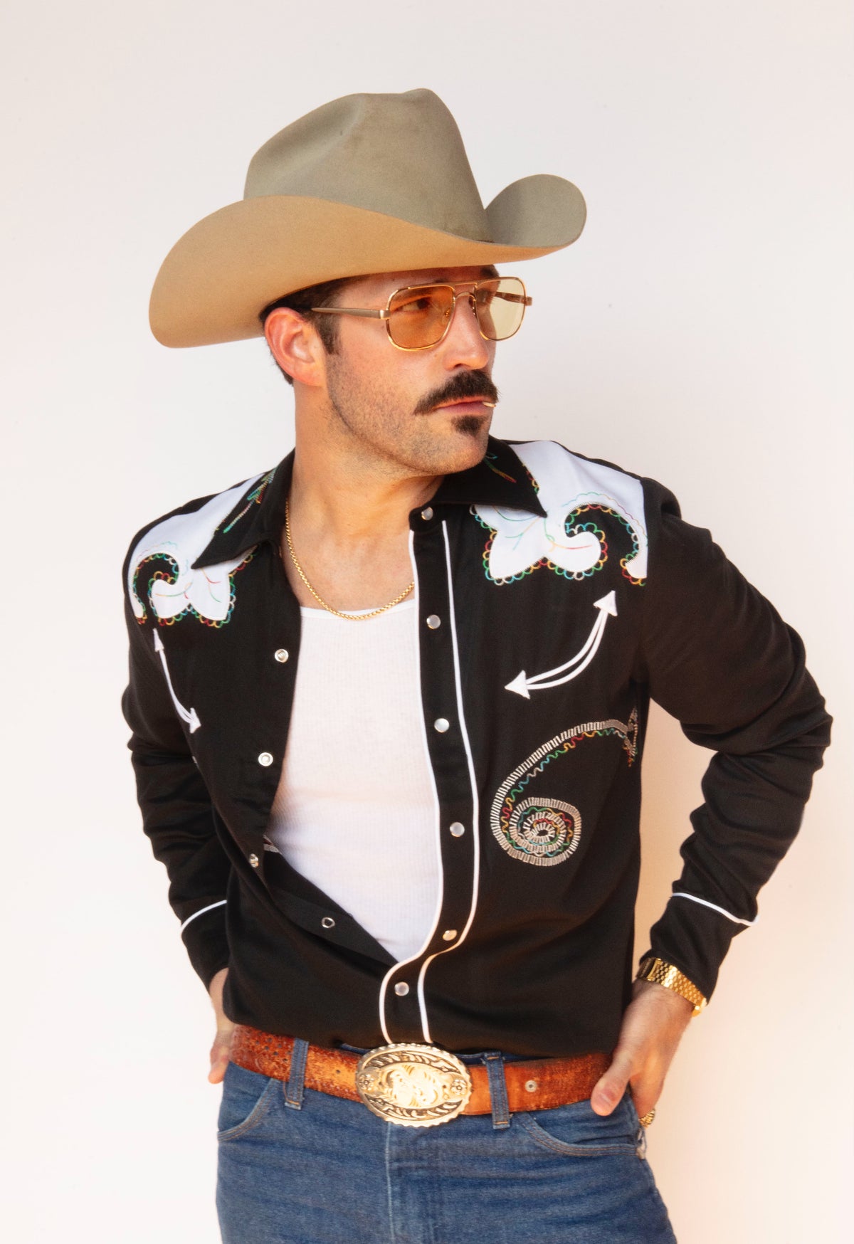 Man in a cowboy hat and tinted glasses wearing the H Bar C Arrowhead embroidered black shirt.