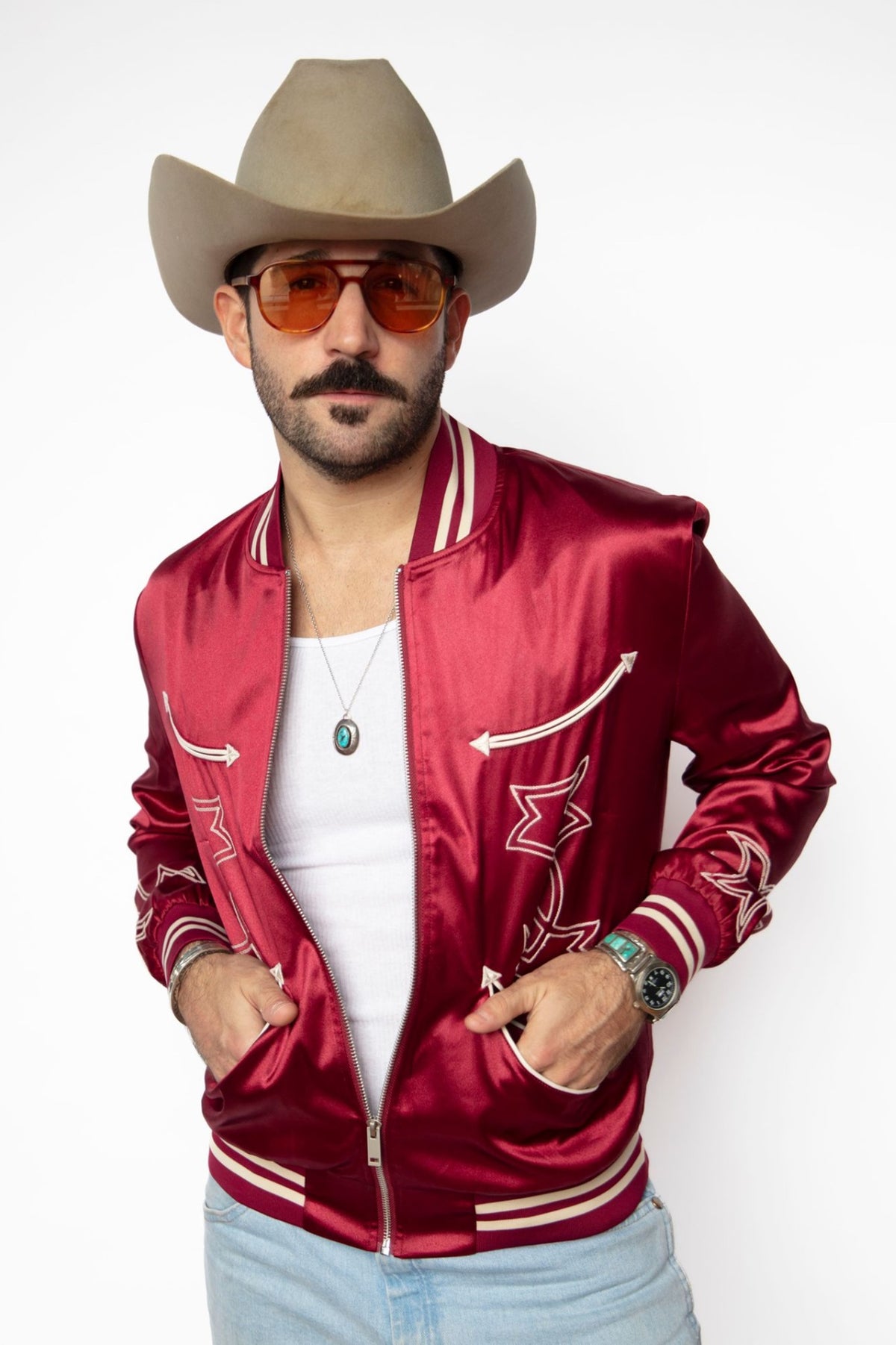 Man in a cowboy hat wearing the H Bar C Odessa unisex tour jacket in red satin with white chain stitch and striped ribbing.