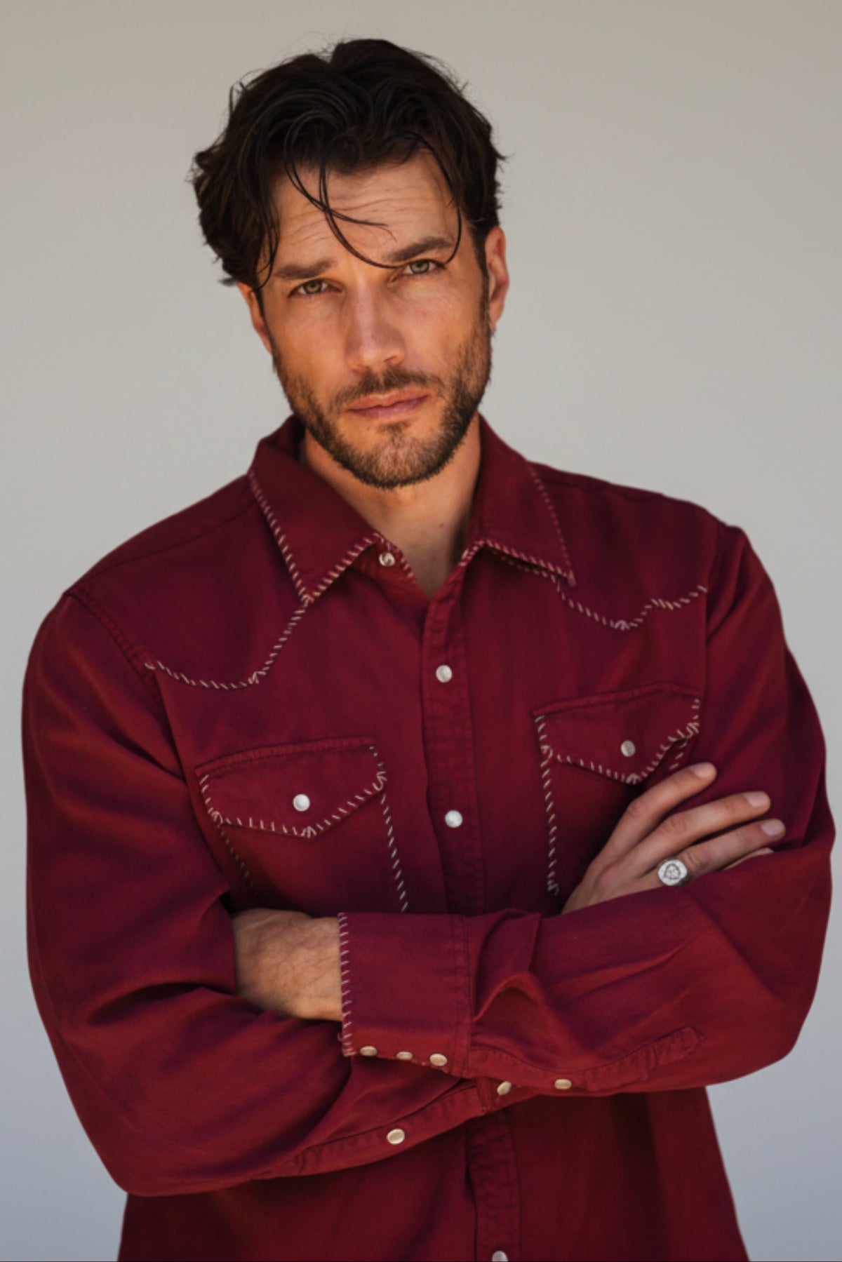 Man with arms crossed wearing the H Bar C Brooklyn men's shirt in wine with white contrast stitching.