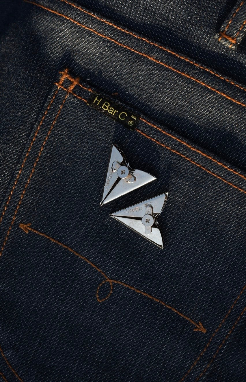 H Bar C silver collar tips with engraved detail laid on an indigo jean pocket.