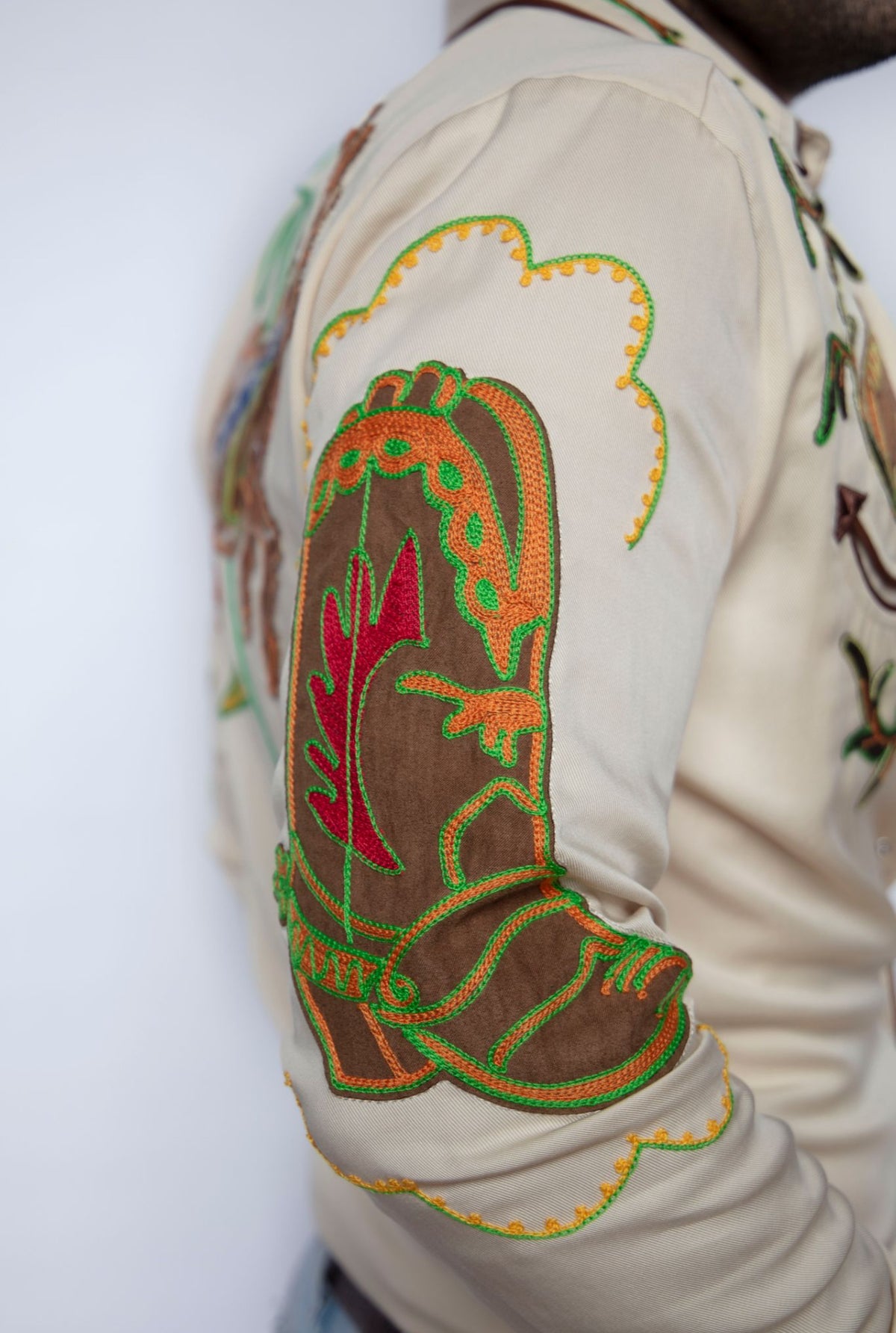 Close-up of the multicolor chain stitch cowboy boot embroidery on the sleeve of the H Bar C Calabasas off-white shirt.