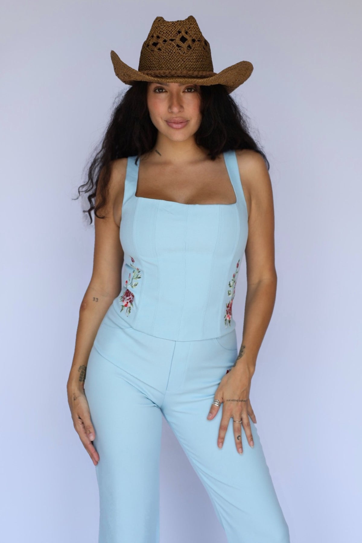 Woman in a straw cowboy hat wearing the H Bar C Abilene blue corset with matching Abilene pants.