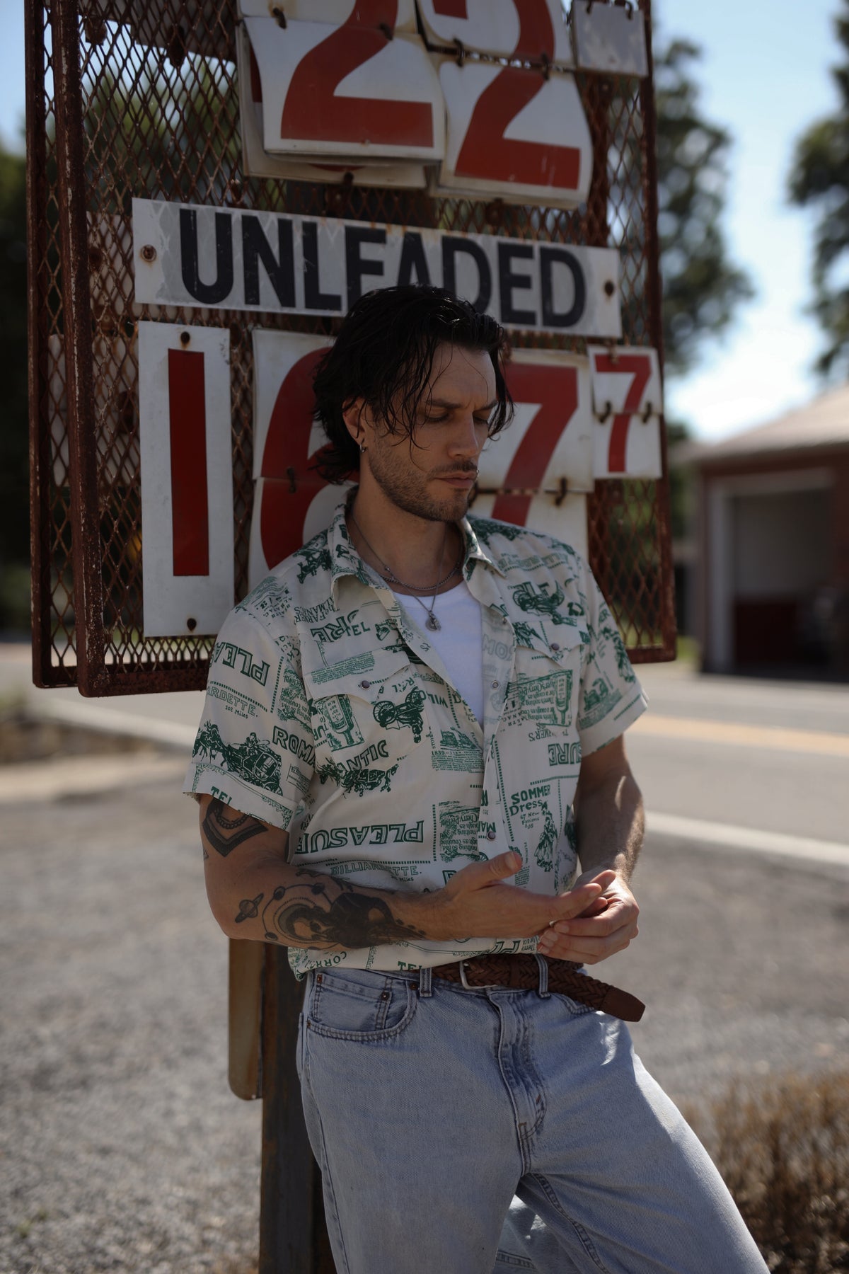 Man outside a vintage gas station wearing the H Bar C Newport Somerville green print short sleeve shirt.