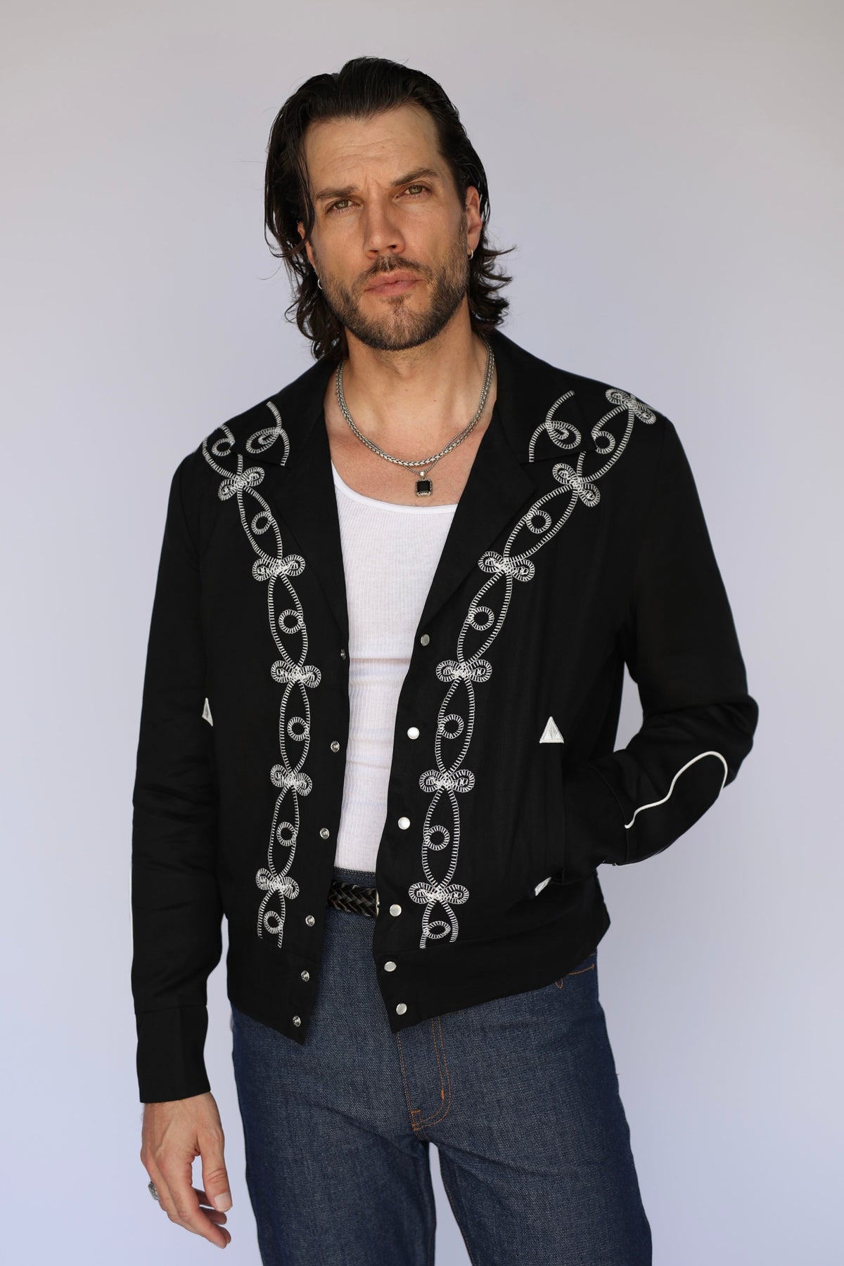 Man wearing the H Bar C Bolero El Patrón men's jacket in black with white soutache embroidery, rebuilt from a pre-1950 H Bar C archive design.