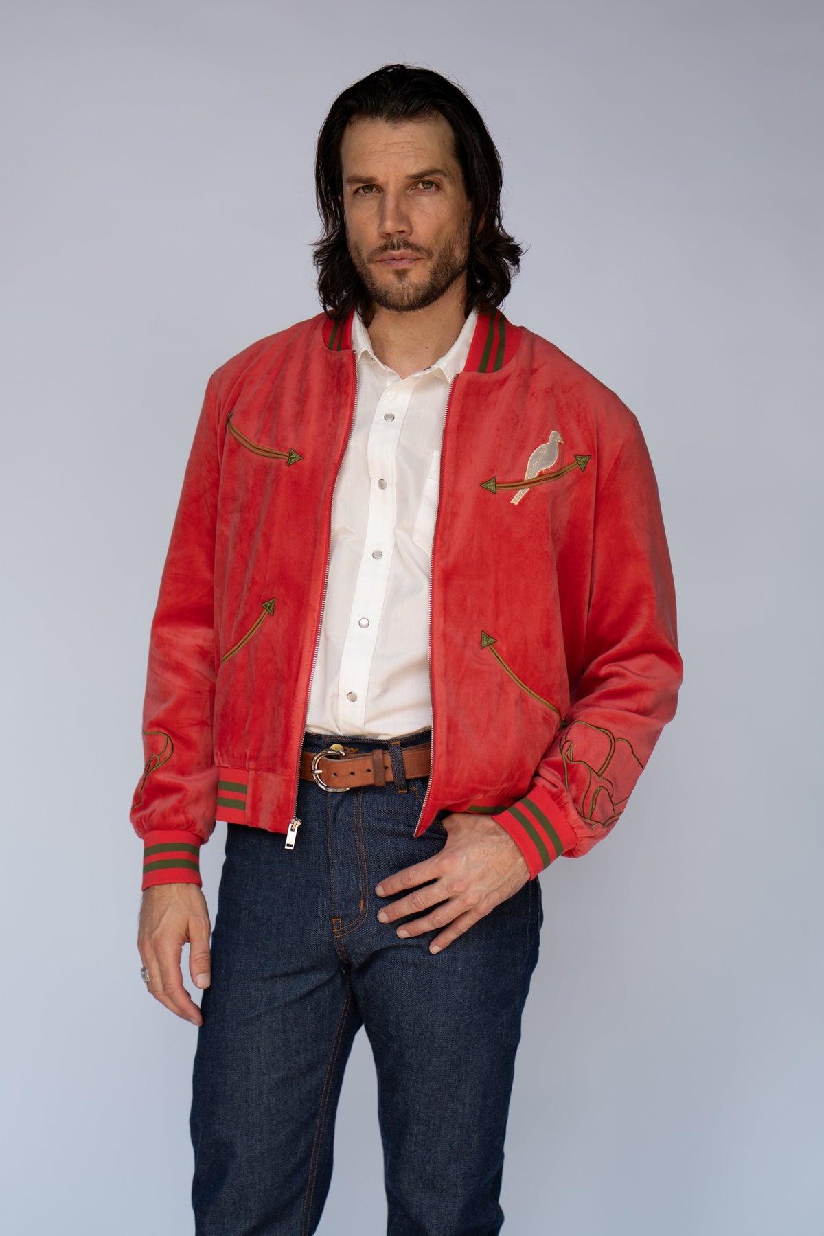 Man wearing the HBarC x Gibson Dove unisex tour jacket in red velour with green striped ribbing and dove embroidery.