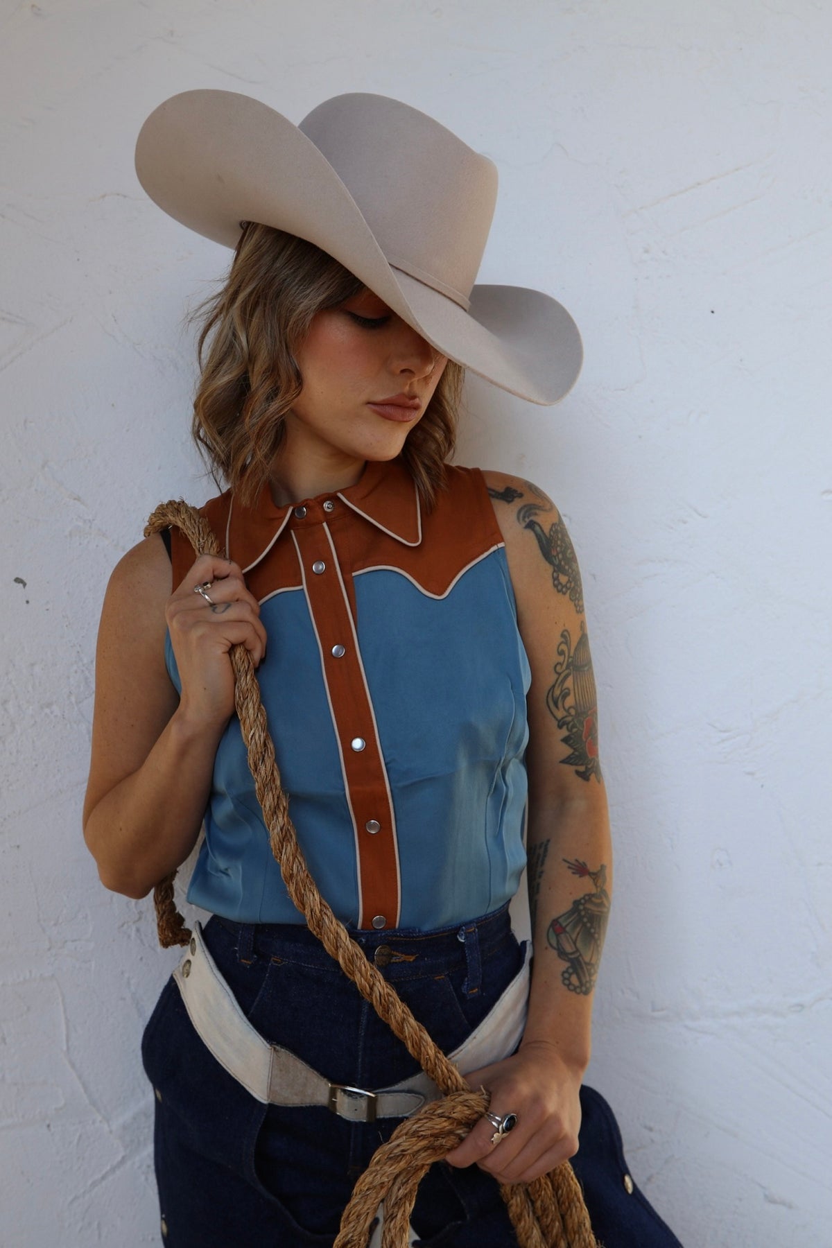 Woman in a cowboy hat wearing the H Bar C Atlanta women's sleeveless shirt in Columbia blue with caramel yokes.