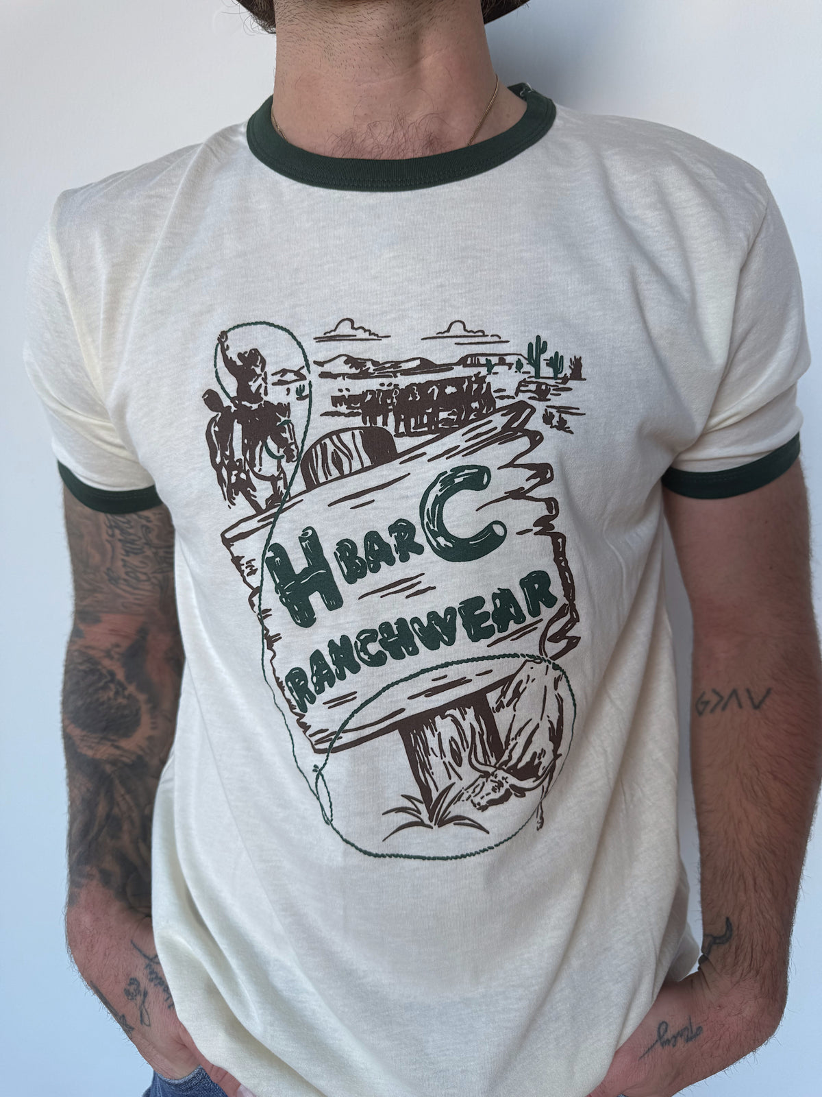 Front view of the H Bar C Post Canyon off white and green ringer T-shirt with H Bar C Ranchwear vintage ad graphic.