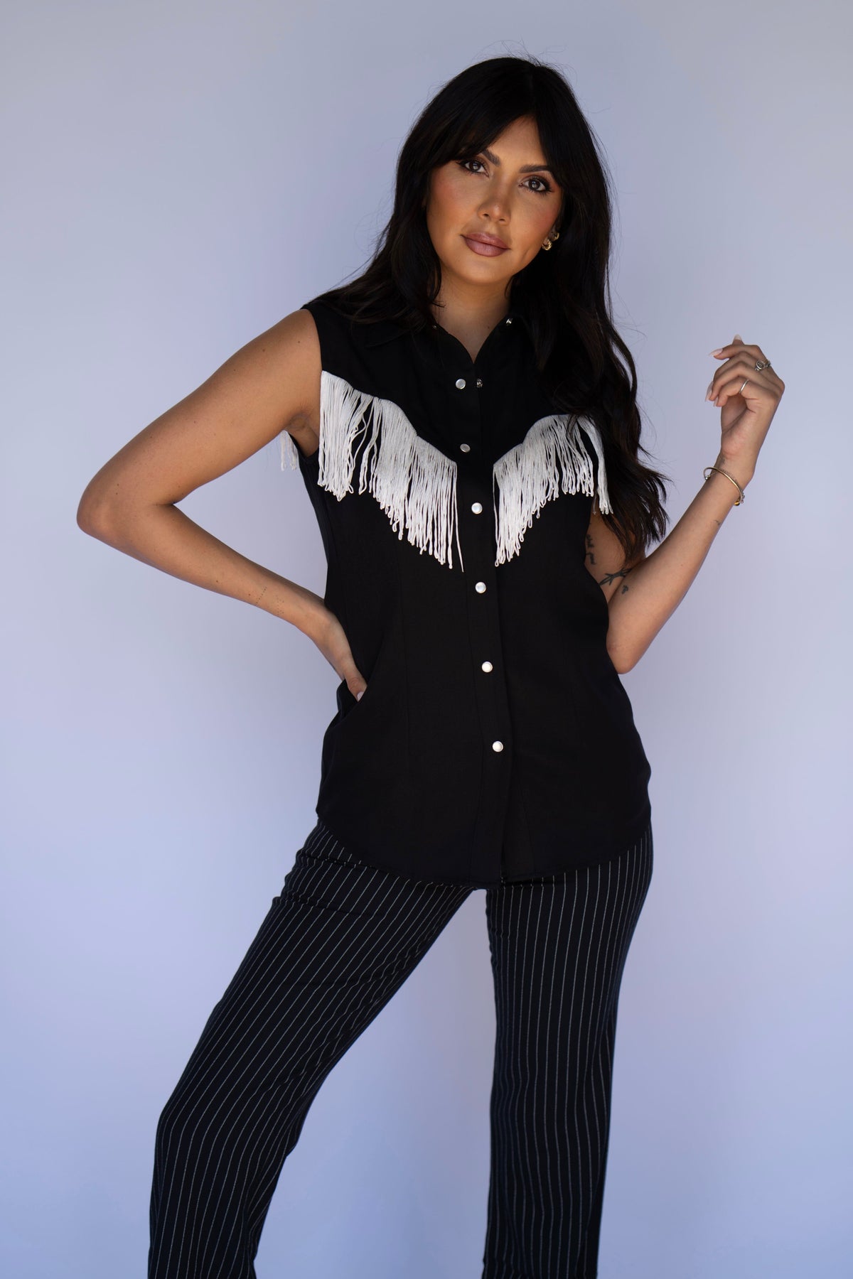 Front view of the H Bar C Tulsa black sleeveless fringe top with pinstripe trousers.