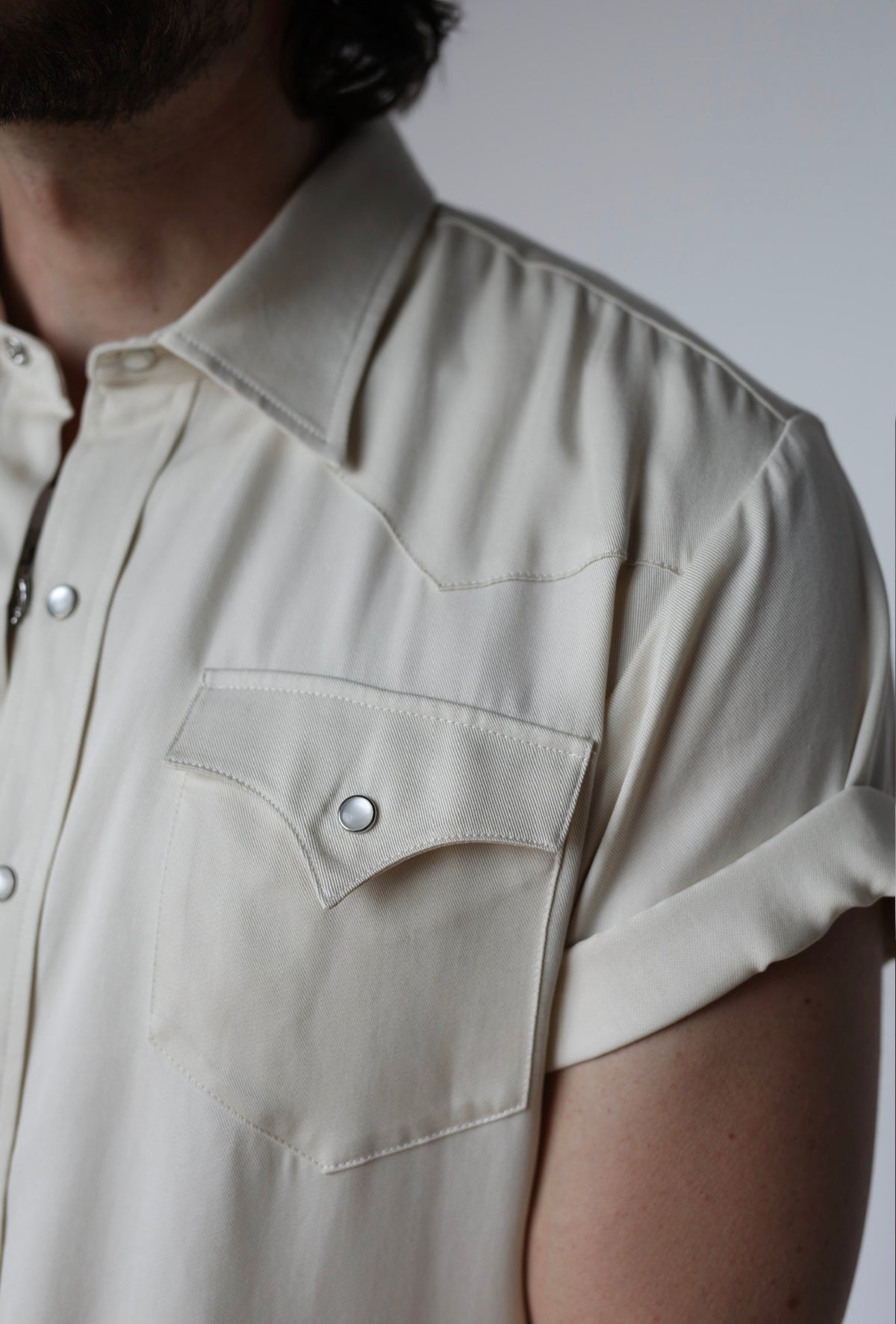 Close-up of the pointed chest pocket and pearl snaps on the H Bar C Newport off white short sleeve shirt.