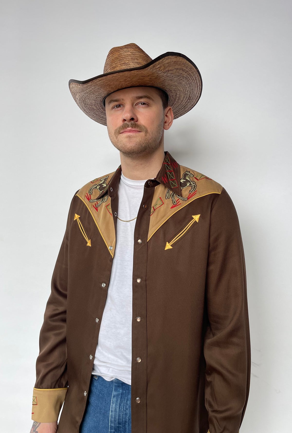 H Bar C Bozeman brown western shirt worn open over a white tee with a cowboy hat.