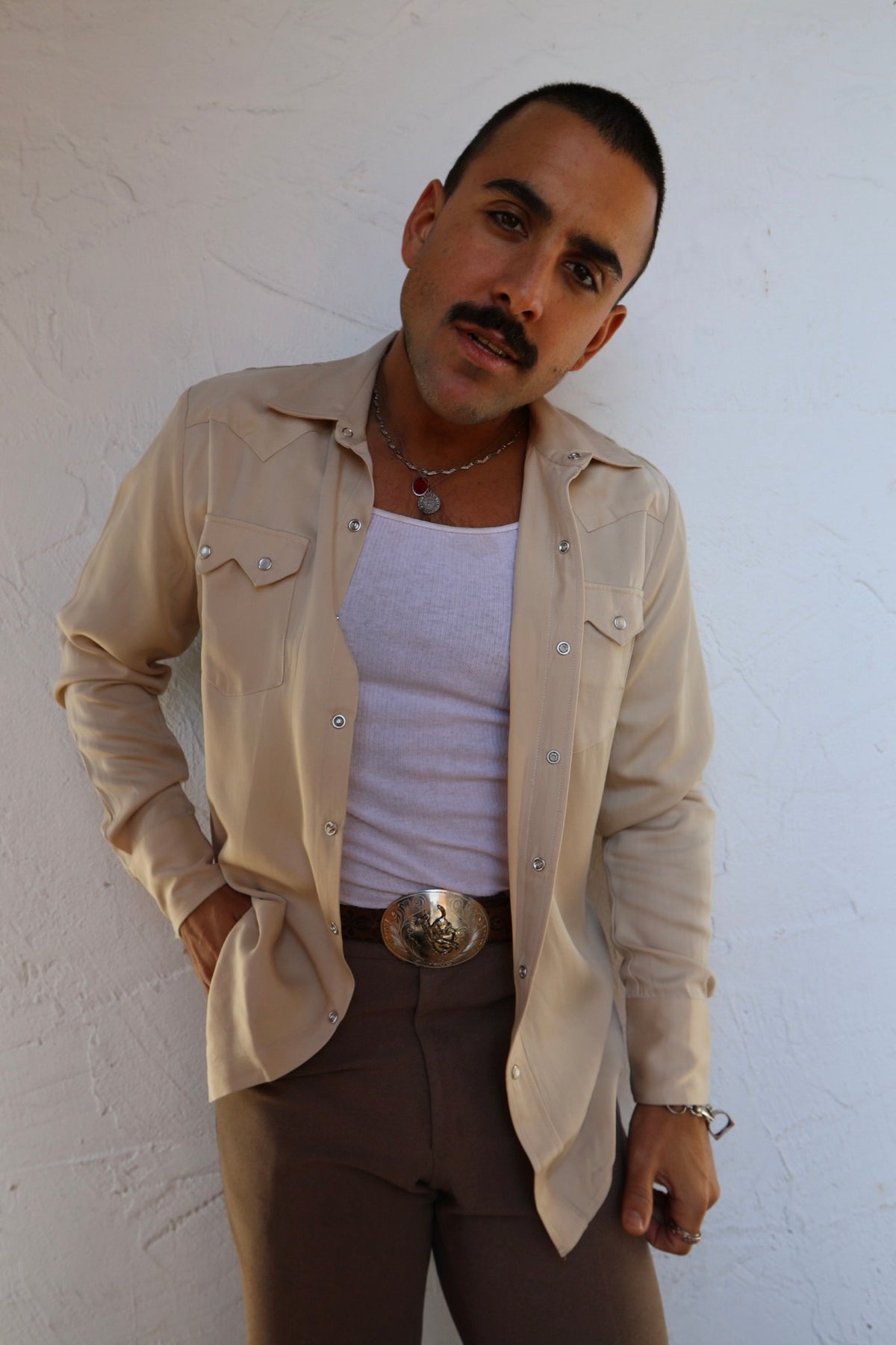 Man wearing the H Bar C Kansas City shirt in beige, a Tencel western shirt with sawtooth pockets, open over a white tank with brown pants.