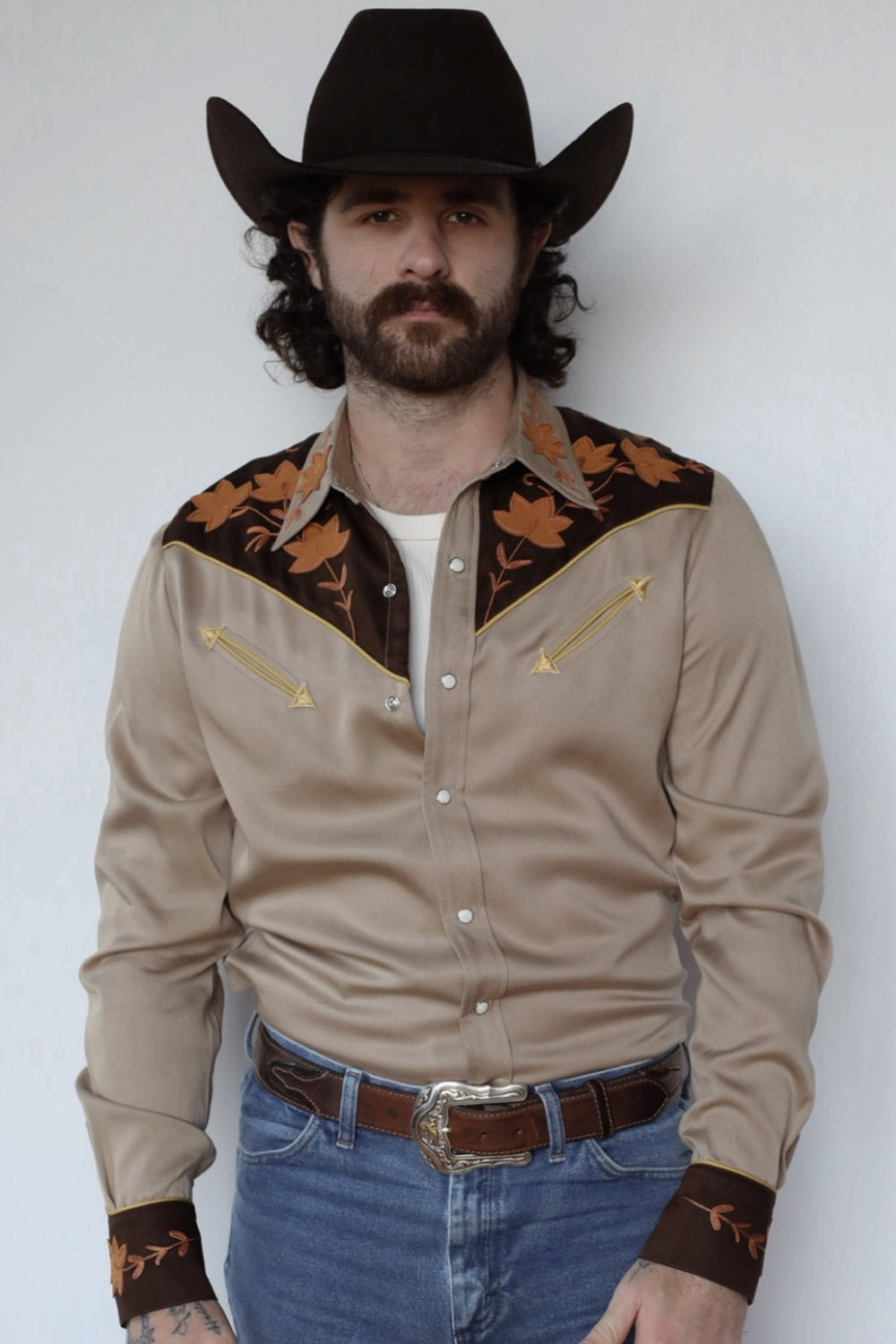 Man in a black cowboy hat wearing the H Bar C Stowe shirt in sandstone with dark brown yokes and orange leaf embroidery.
