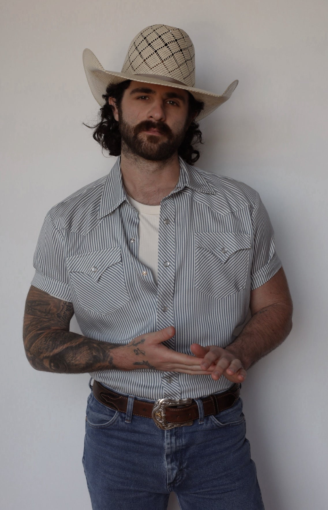 Front view of the H Bar C Newport gray pinstripe short sleeve western shirt tucked into jeans with a straw hat.