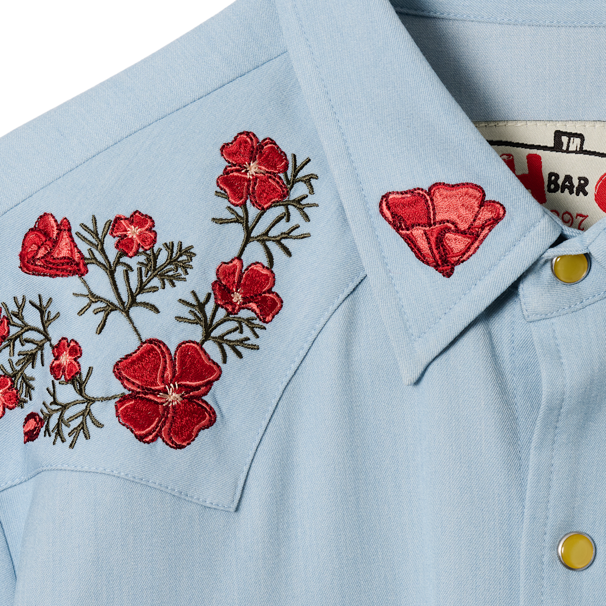 Collar and yoke detail of the HBarC x Gibson Dove light blue chambray shirt with red poppy and green vine embroidery.