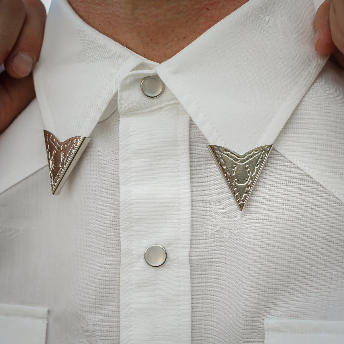 Pair of H Bar C engraved collar tips on a white western shirt collar.