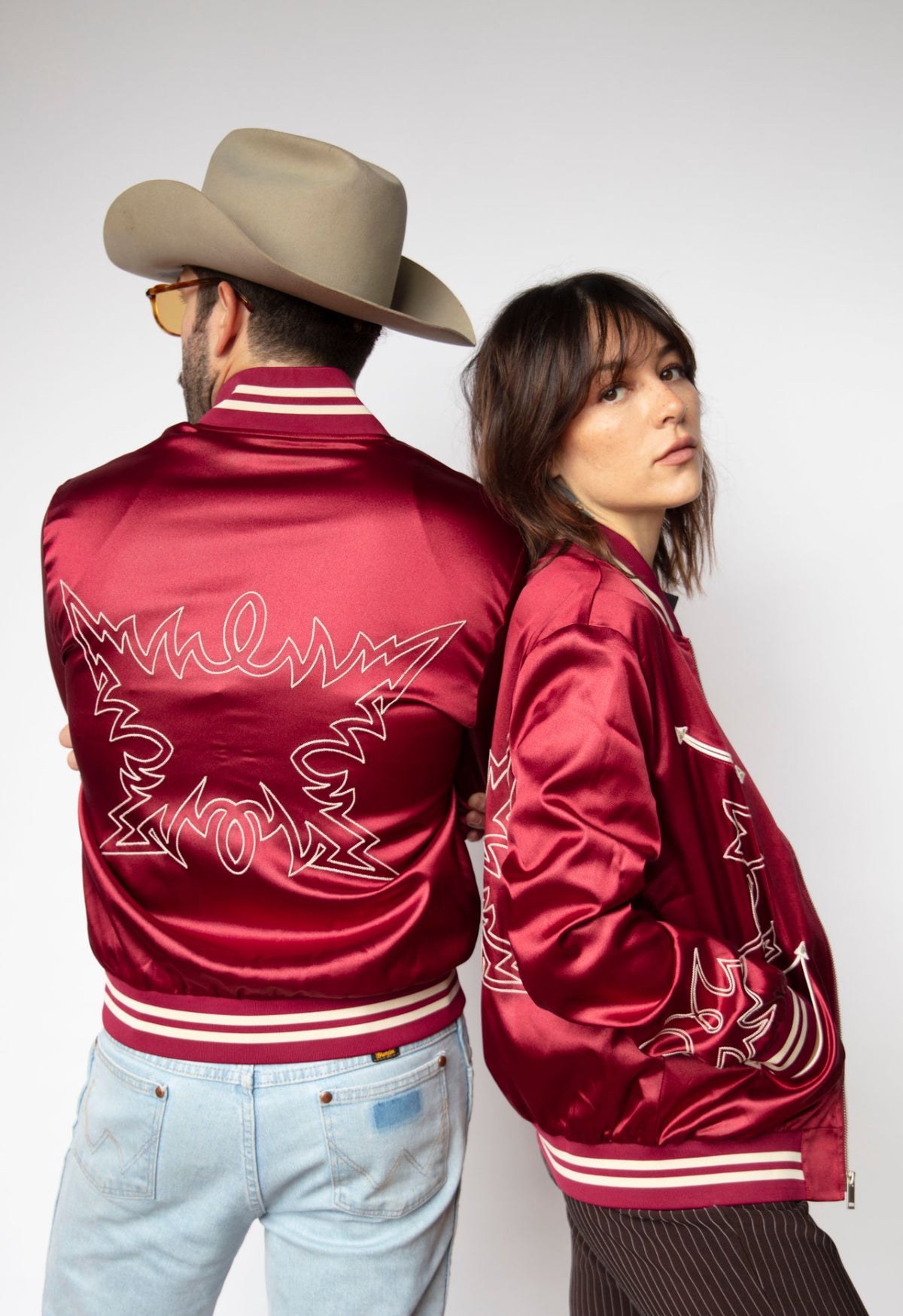 Back view of a couple in H Bar C Odessa red satin tour jackets.
