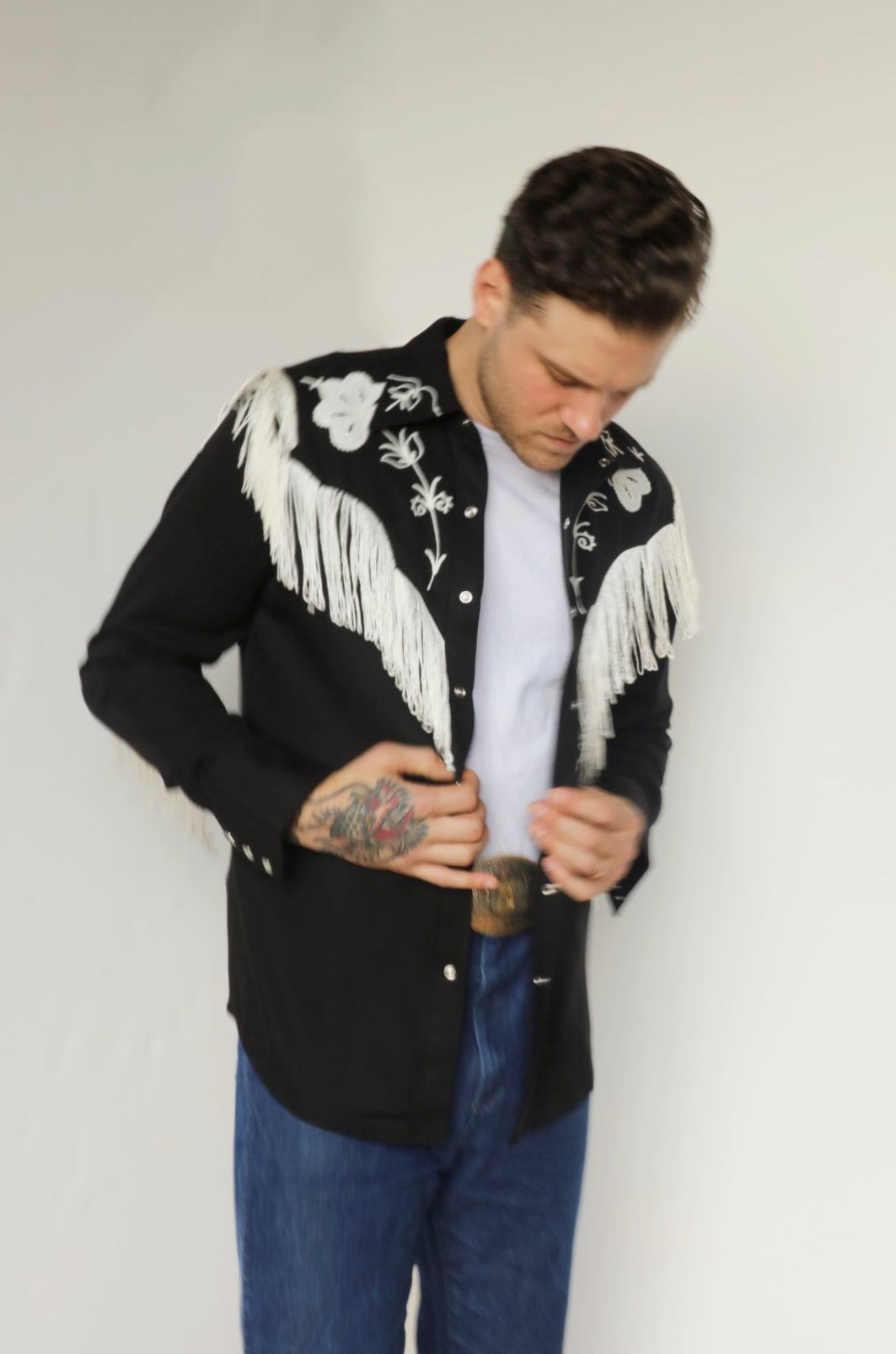 Man buttoning the H Bar C Taos black western shirt with white fringe and floral embroidery on the yokes.