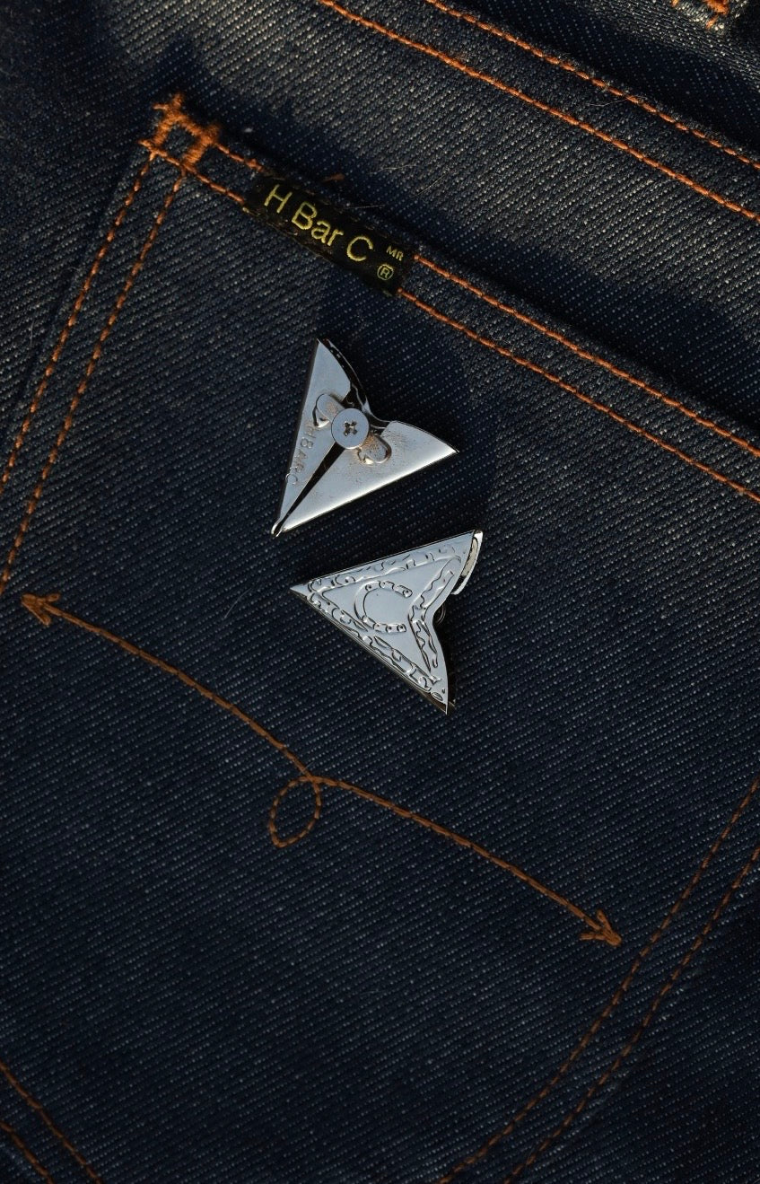 Close-up of the engraved scroll pattern on H Bar C silver collar tips on denim.