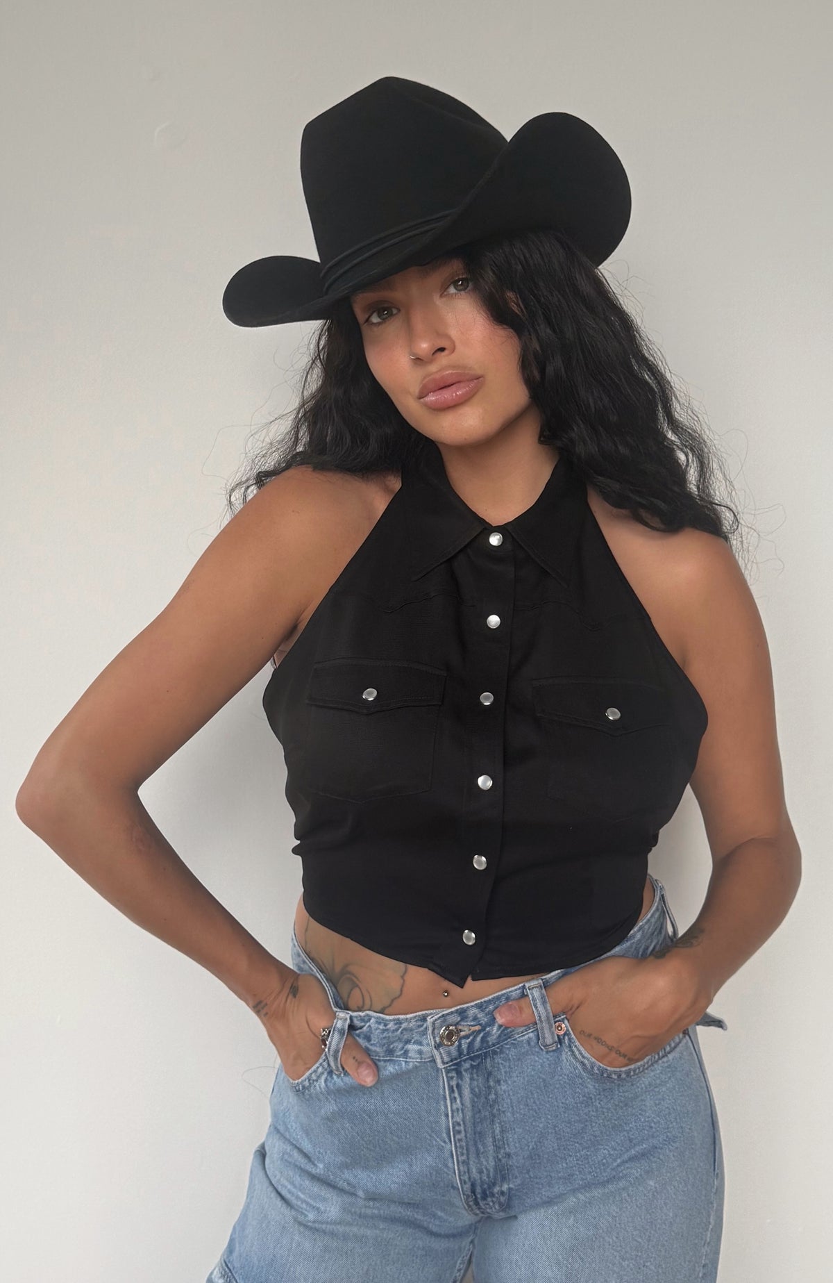 Woman with hands on hips wearing the H Bar C Hampton black western halter top and jeans.