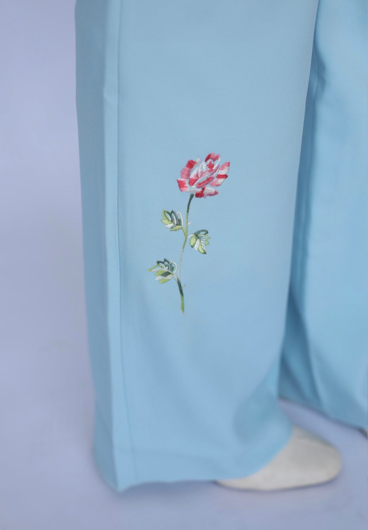 Close-up of the embroidered pink rose on the leg of the H Bar C Abilene light blue flare pants.