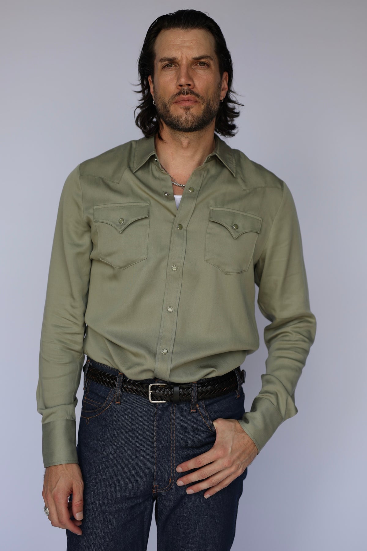 Man wearing the H Bar C Denver men's shirt in sage green, a classic Tencel pearl snap western shirt, with dark jeans.