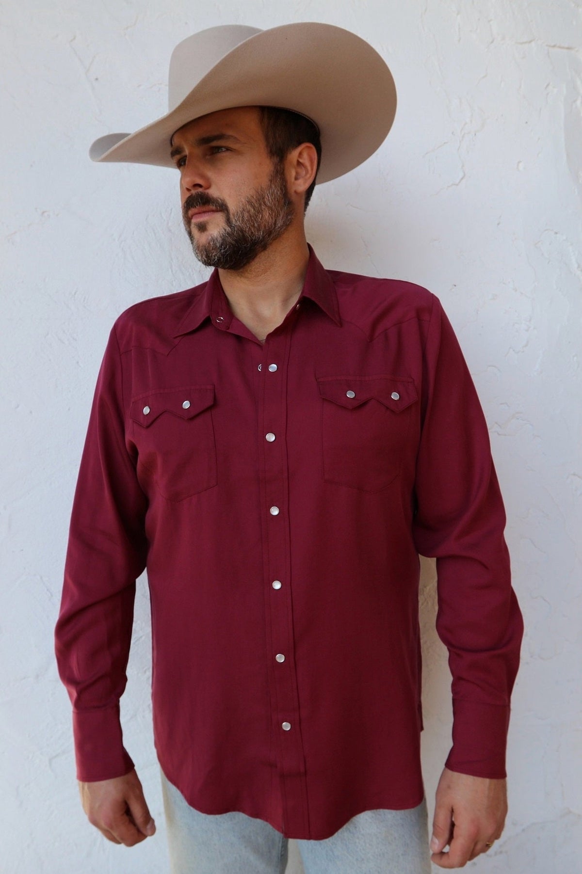 Man in a cowboy hat wearing the H Bar C Kansas City shirt in wine with sawtooth pockets and pearl snaps.