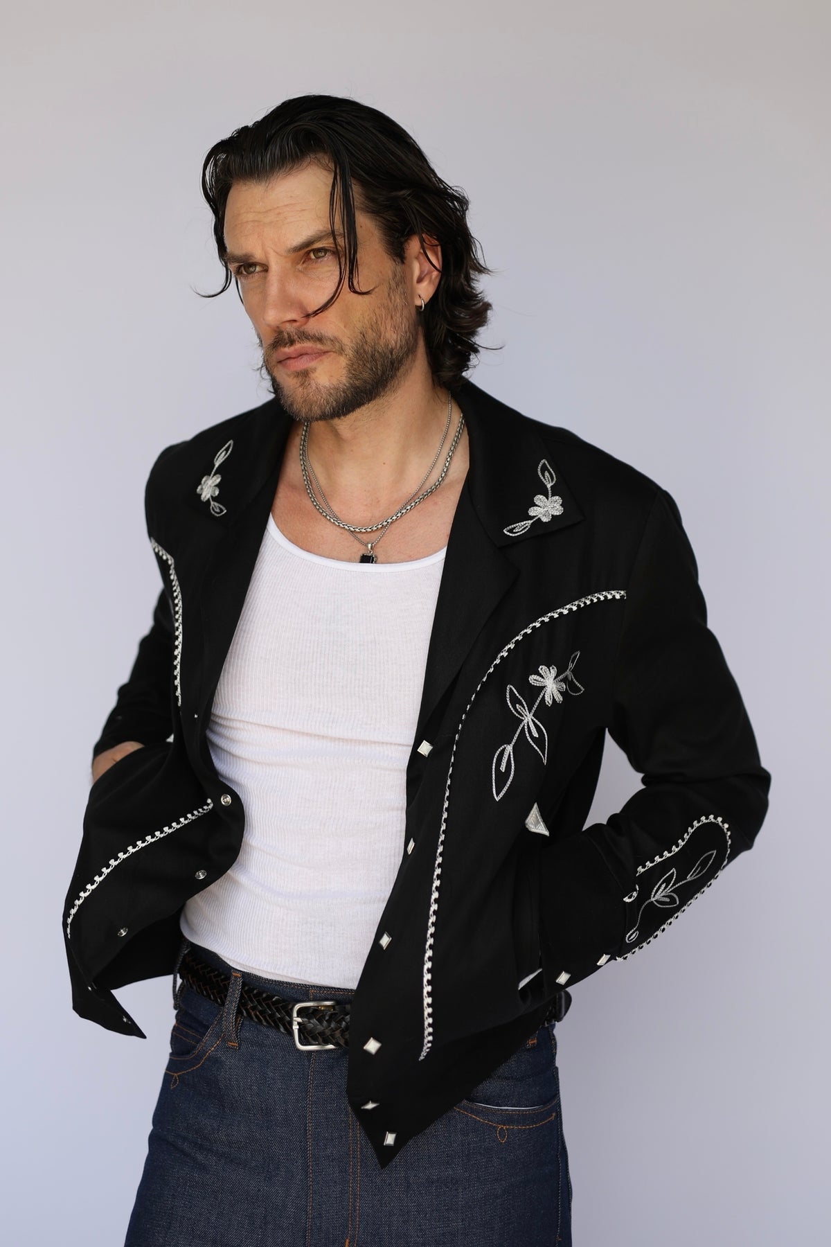 Man in the H Bar C Bolero Nogales black jacket worn open over a white tank with jeans.