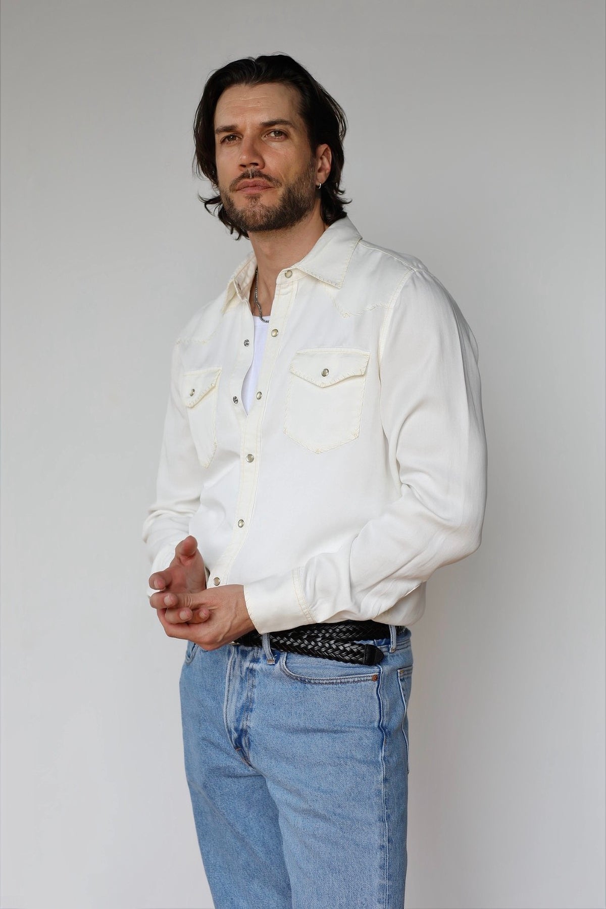 Man wearing the H Bar C Brooklyn men's shirt in off-white with tonal accent stitching and pearl snaps, with light jeans.
