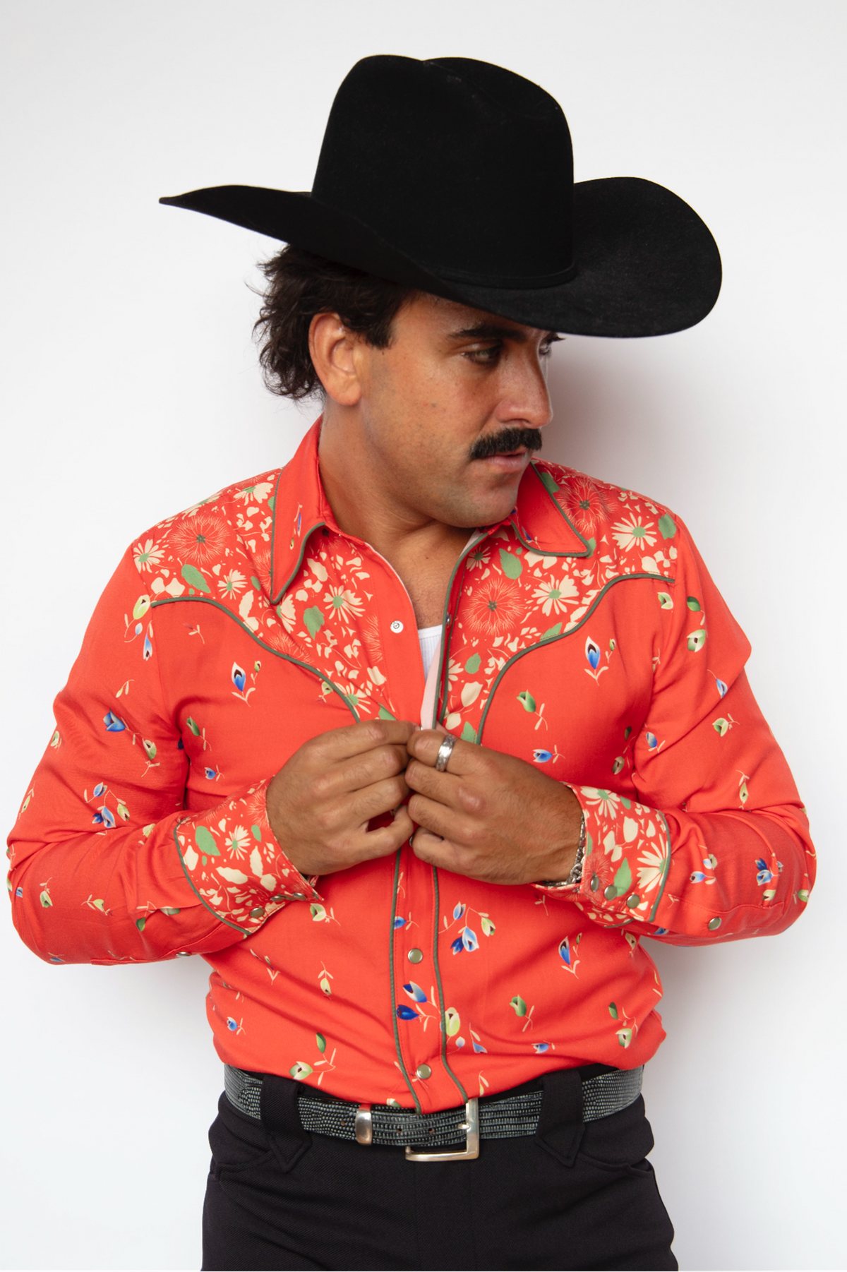 Man in a black cowboy hat wearing the H Bar C Midlands shirt in red with a multicolor floral print, a 1970s rock and roll western shirt.