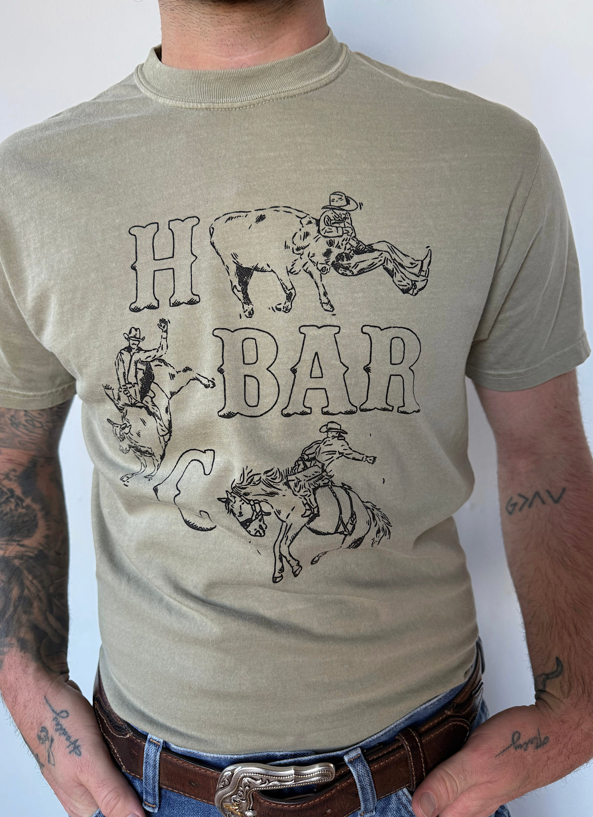 Close-up of the hand-drawn H Bar C bucking bronco graphic on the green Busted Spur T-shirt by Kate Snake Art.