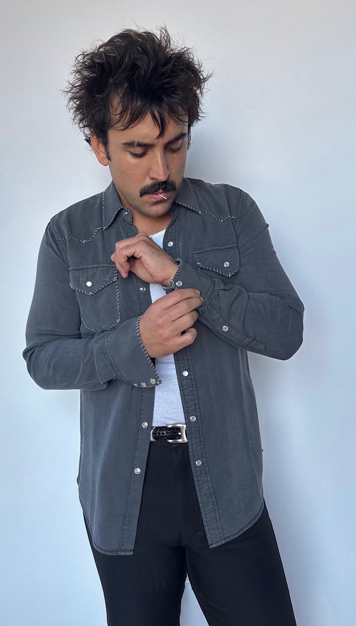 Man fastening the cuff of the H Bar C Brooklyn black western shirt with contrast stitched one point yoke.